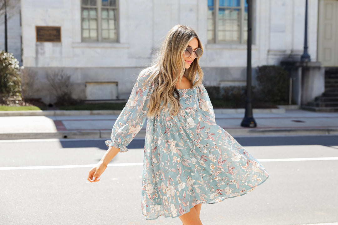model wearing a light blue floral mini dress with sunglasses