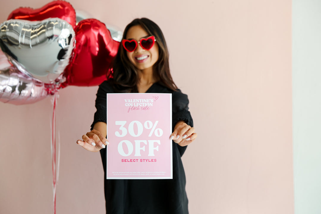 model wearing Valentine's Day outfit and holding 30% off sign