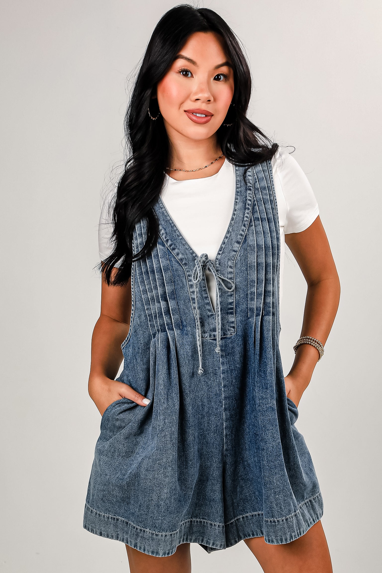 Woman wearing a denim dress over a white shirt on a plain background