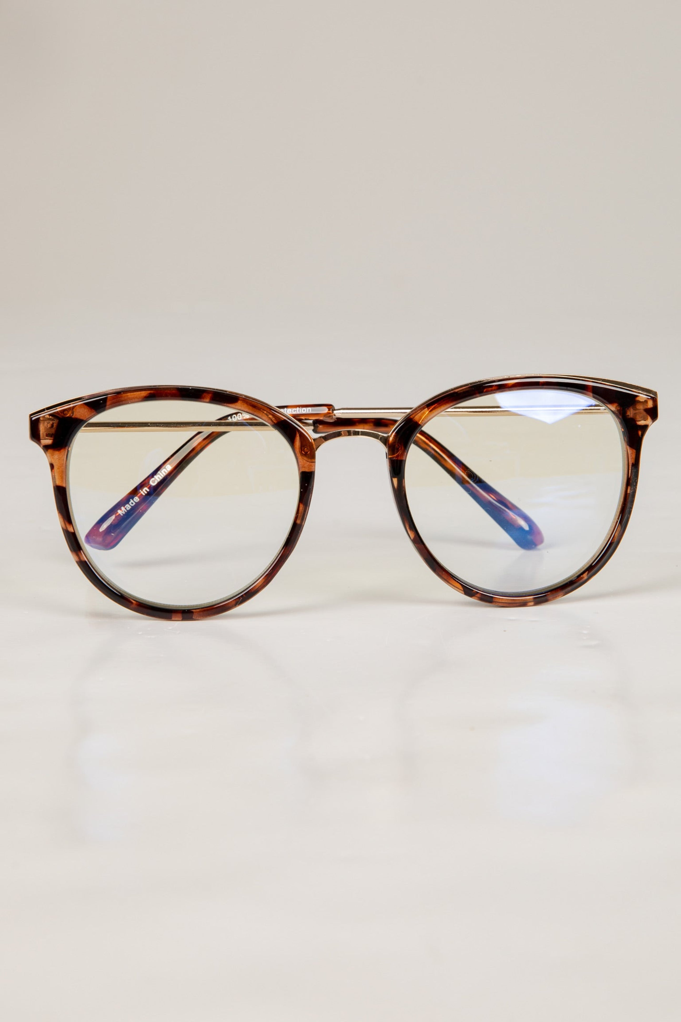 Tortoiseshell eyeglasses on a light beige background
