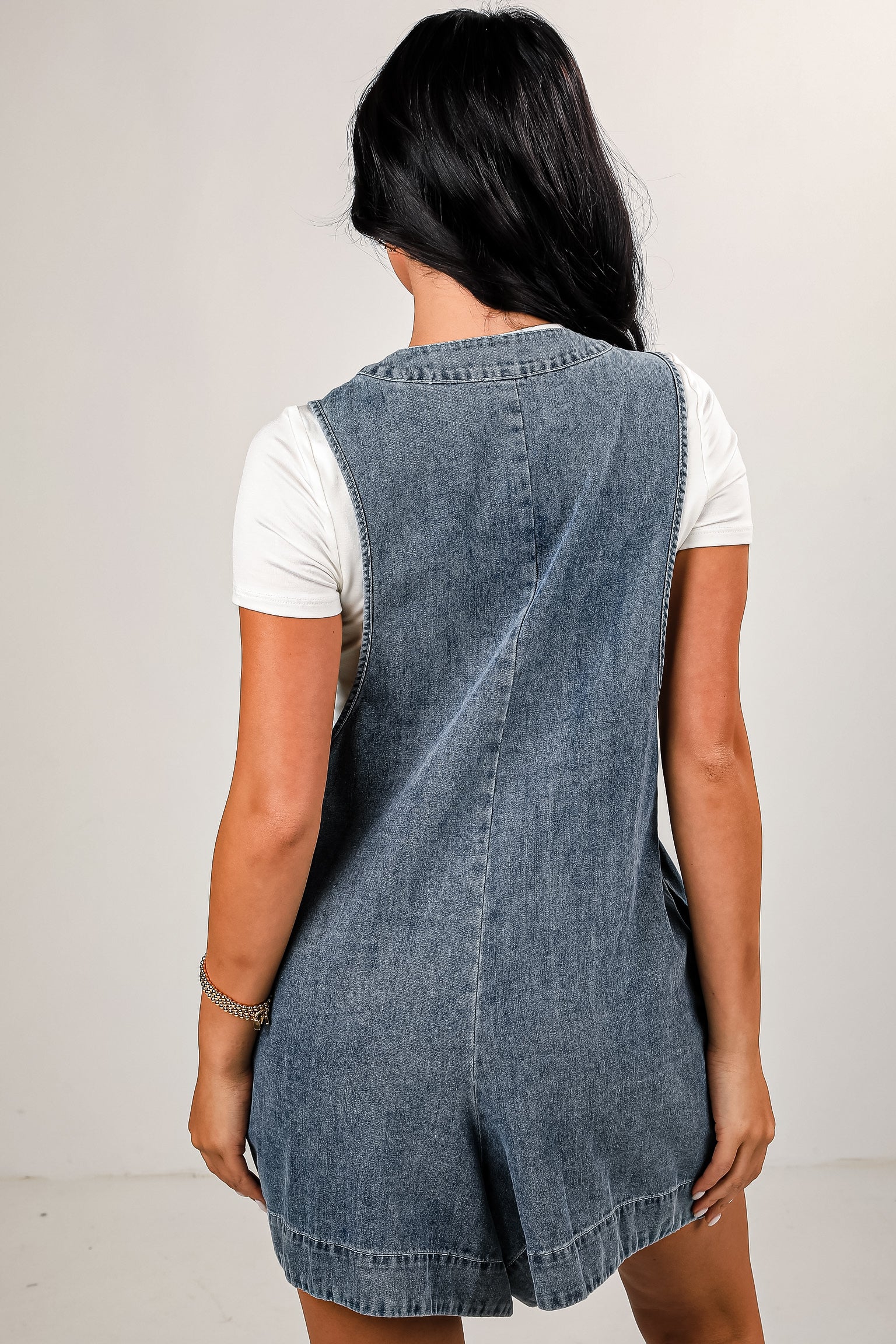 Woman wearing a denim dress over a white shirt on a plain background