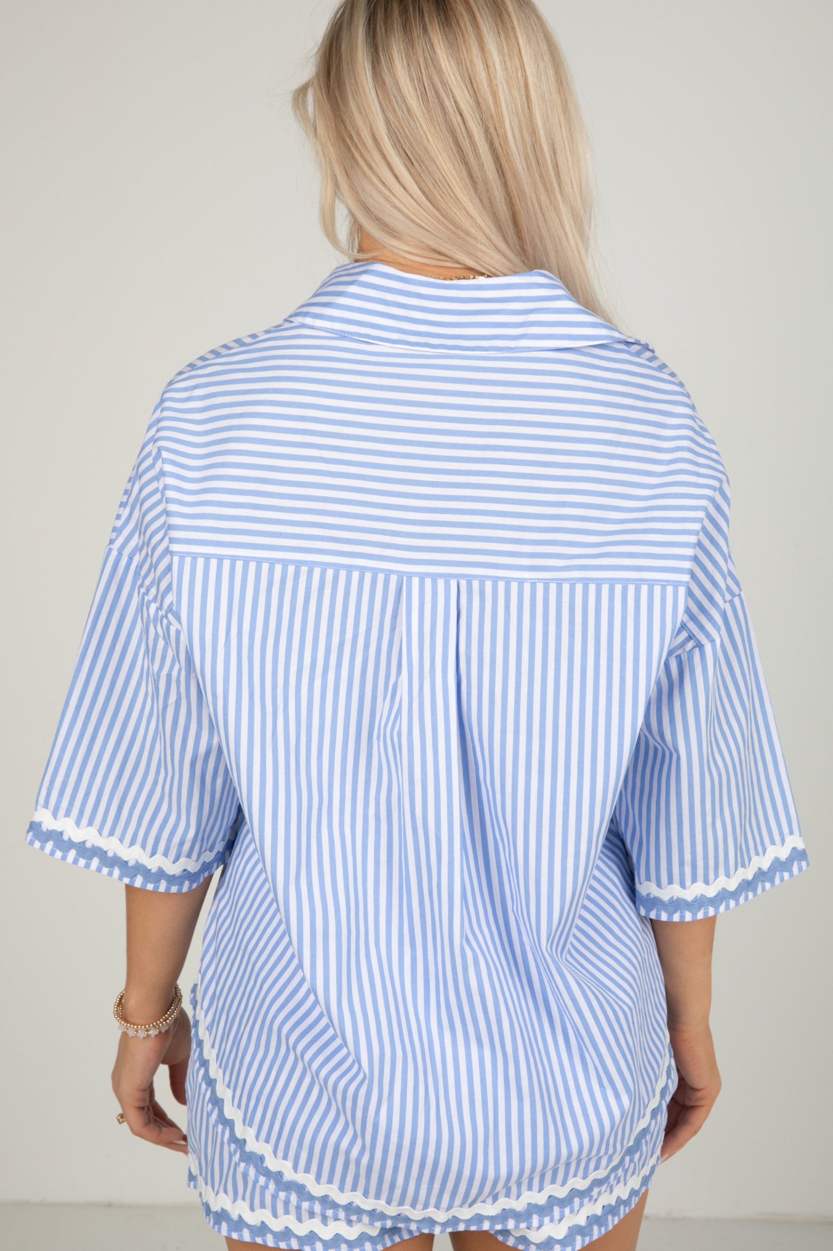Woman wearing a blue and white striped shirt with a plain background