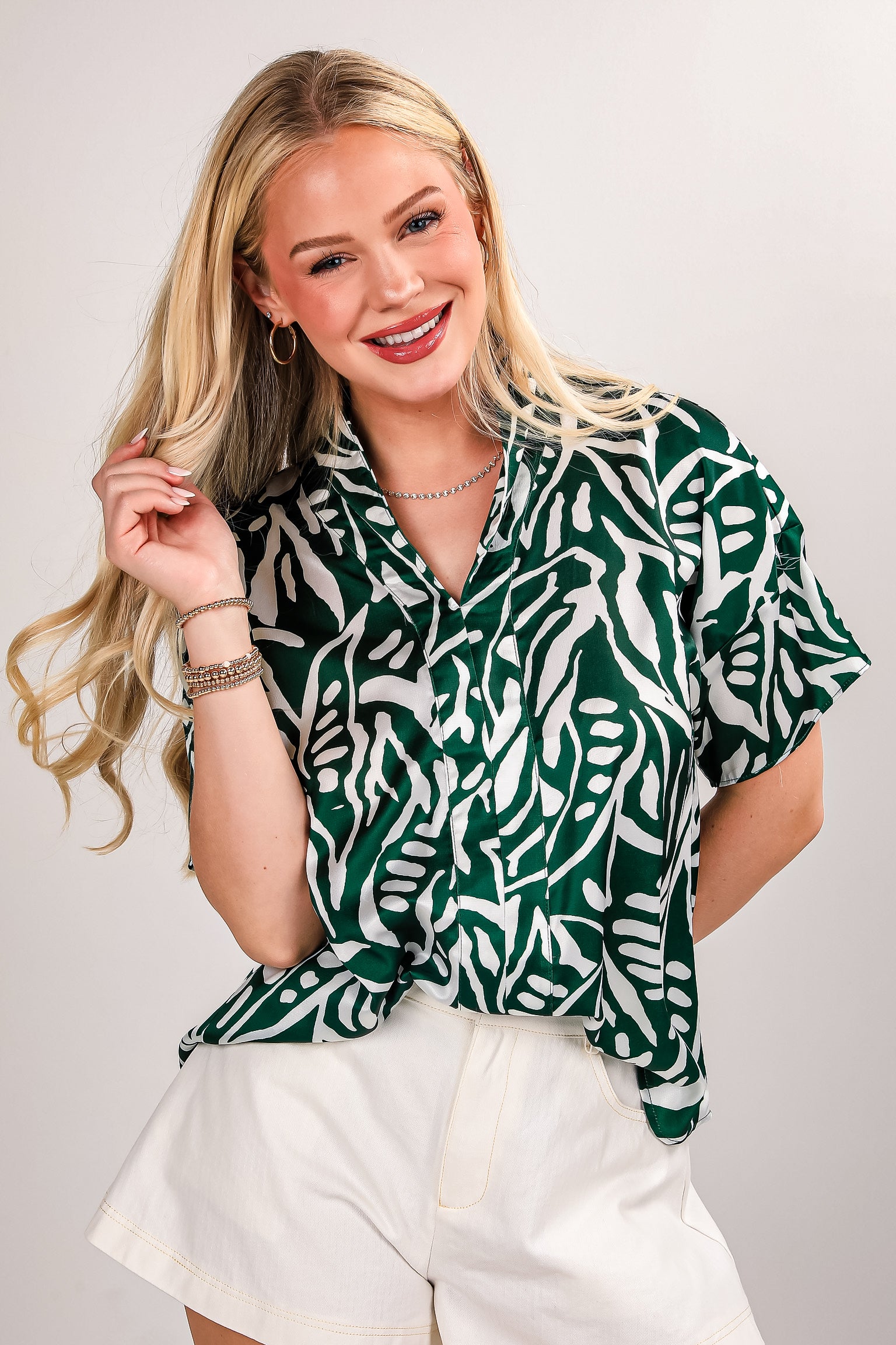 Person wearing a green and white patterned shirt with long blonde hair.