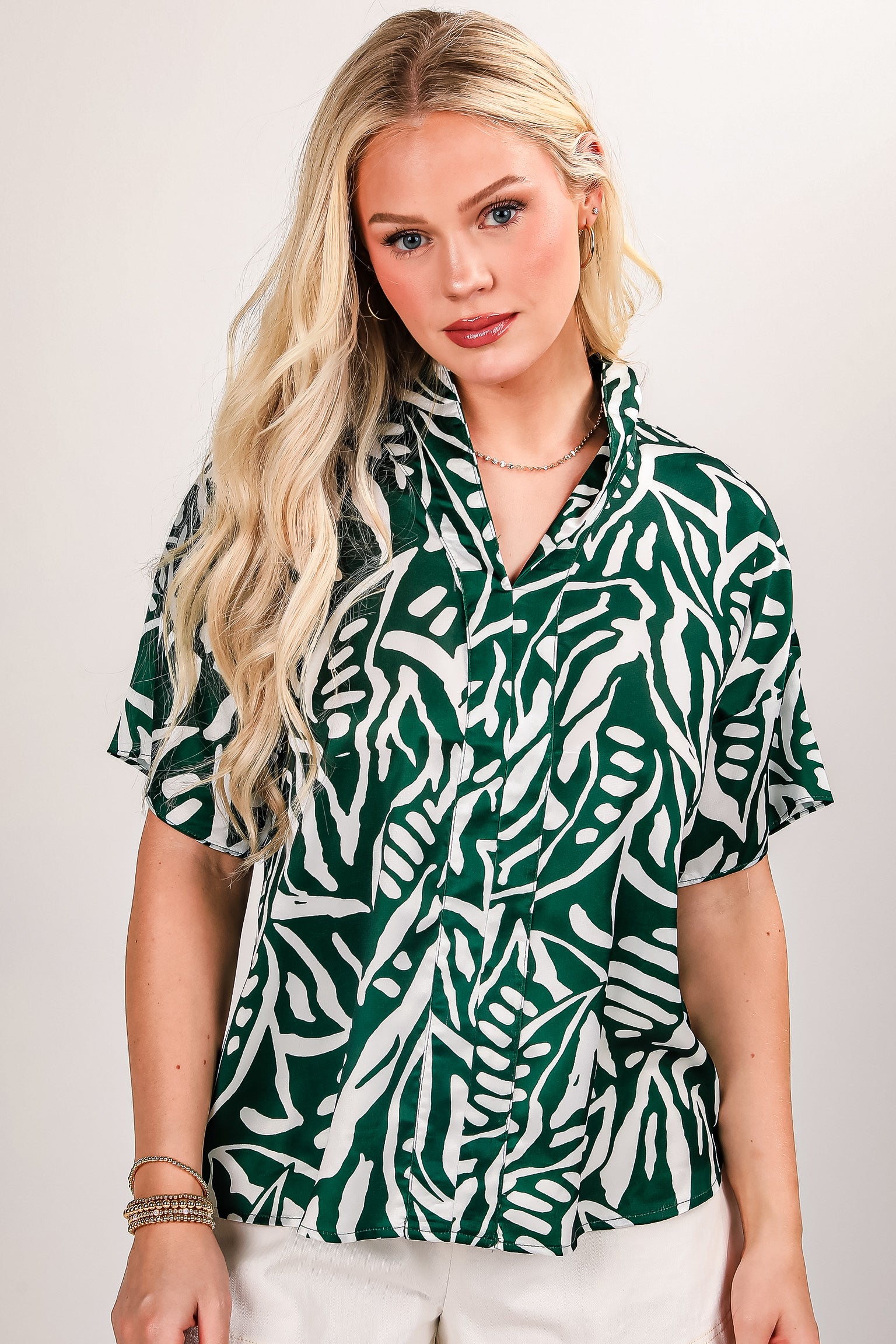 Person wearing a green and white patterned shirt with long blonde hair.