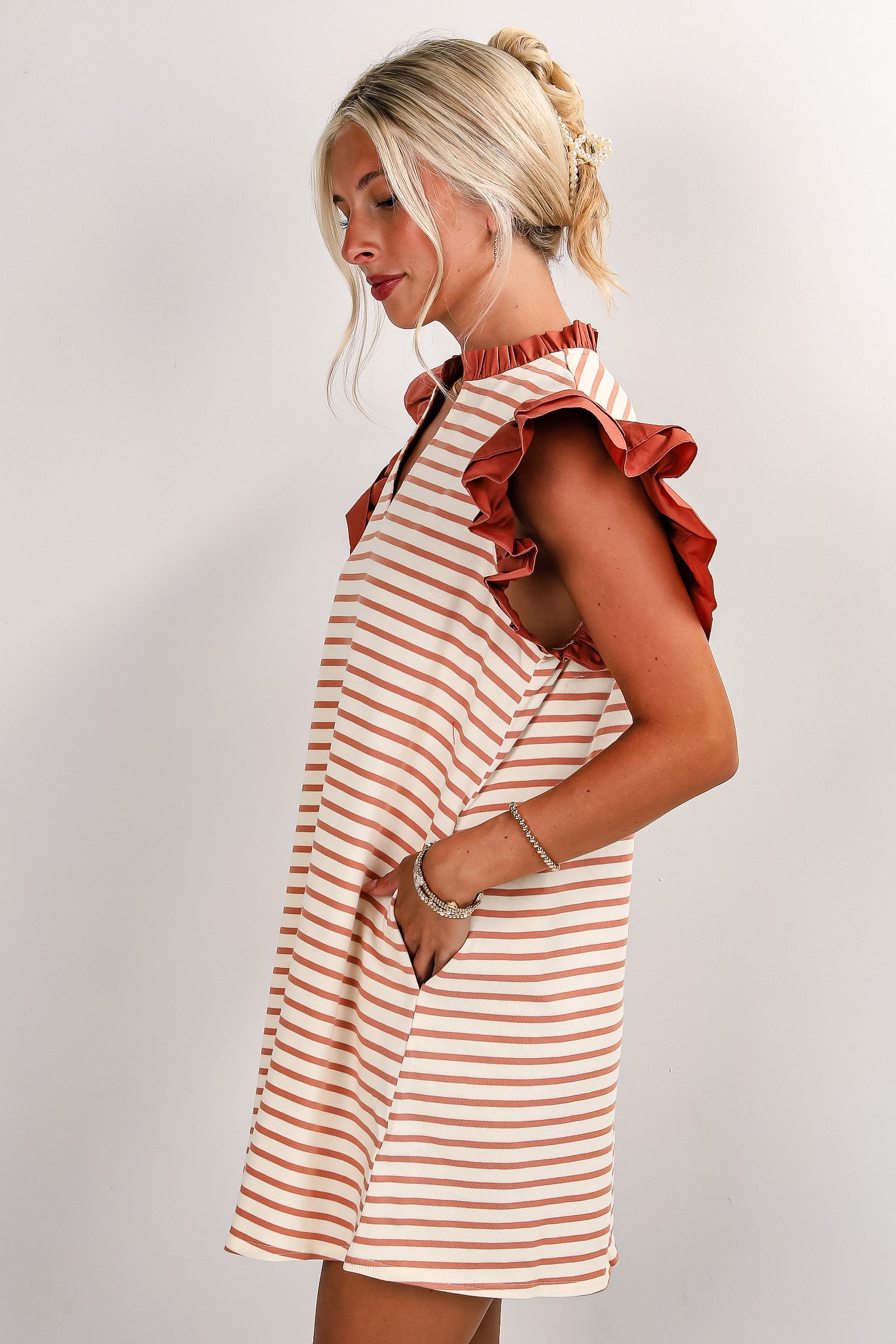 Woman wearing a striped dress with ruffled sleeves against a plain background