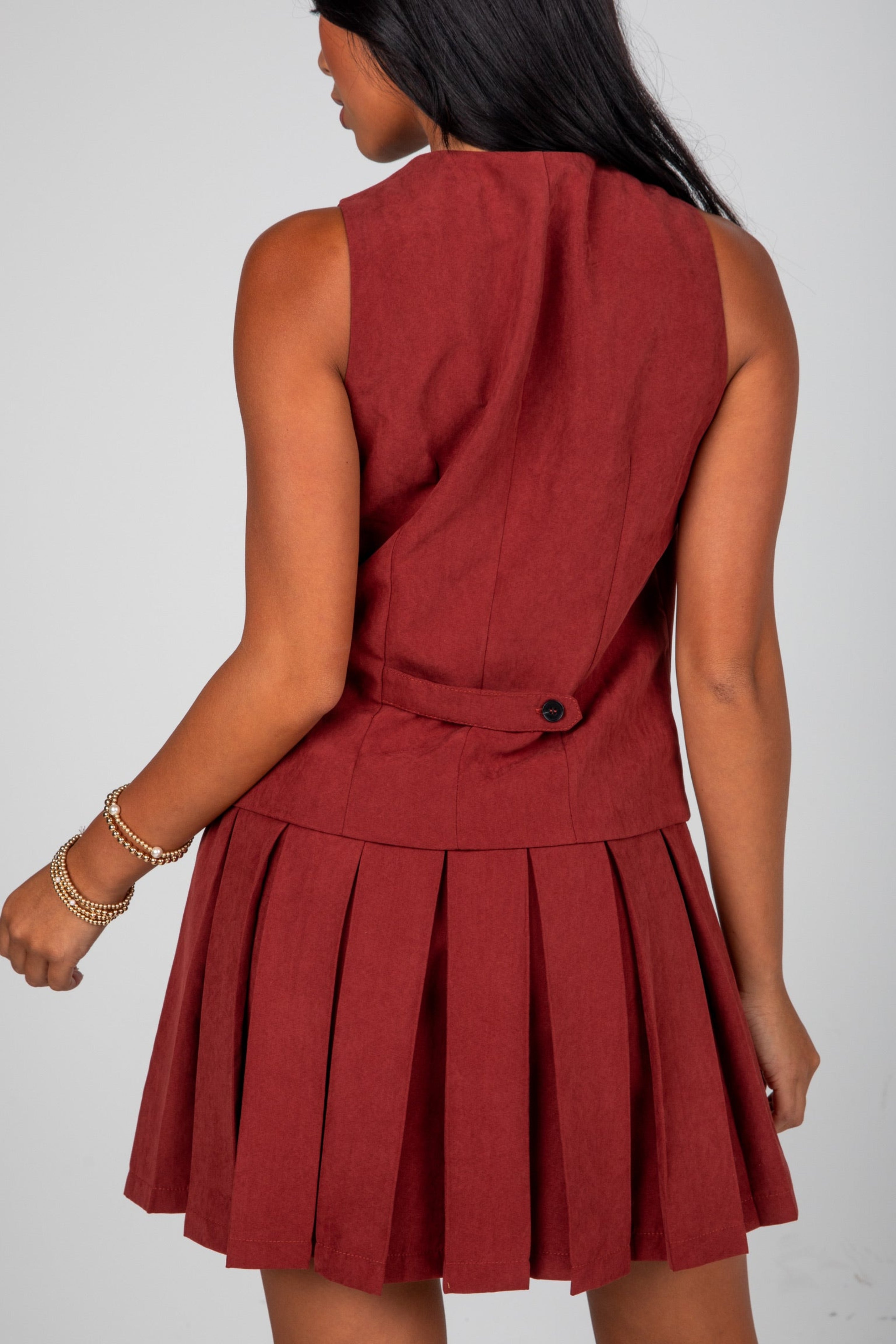 Red dress with pleated skirt worn by a person on a white background