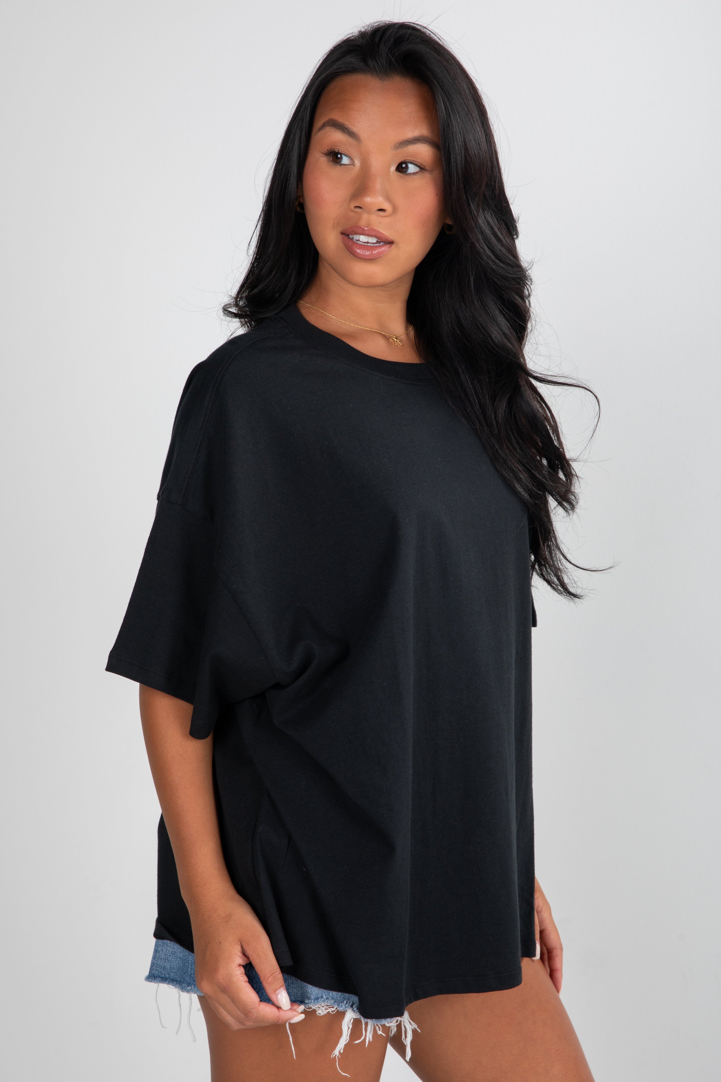 Woman wearing a black oversized t-shirt against a plain background