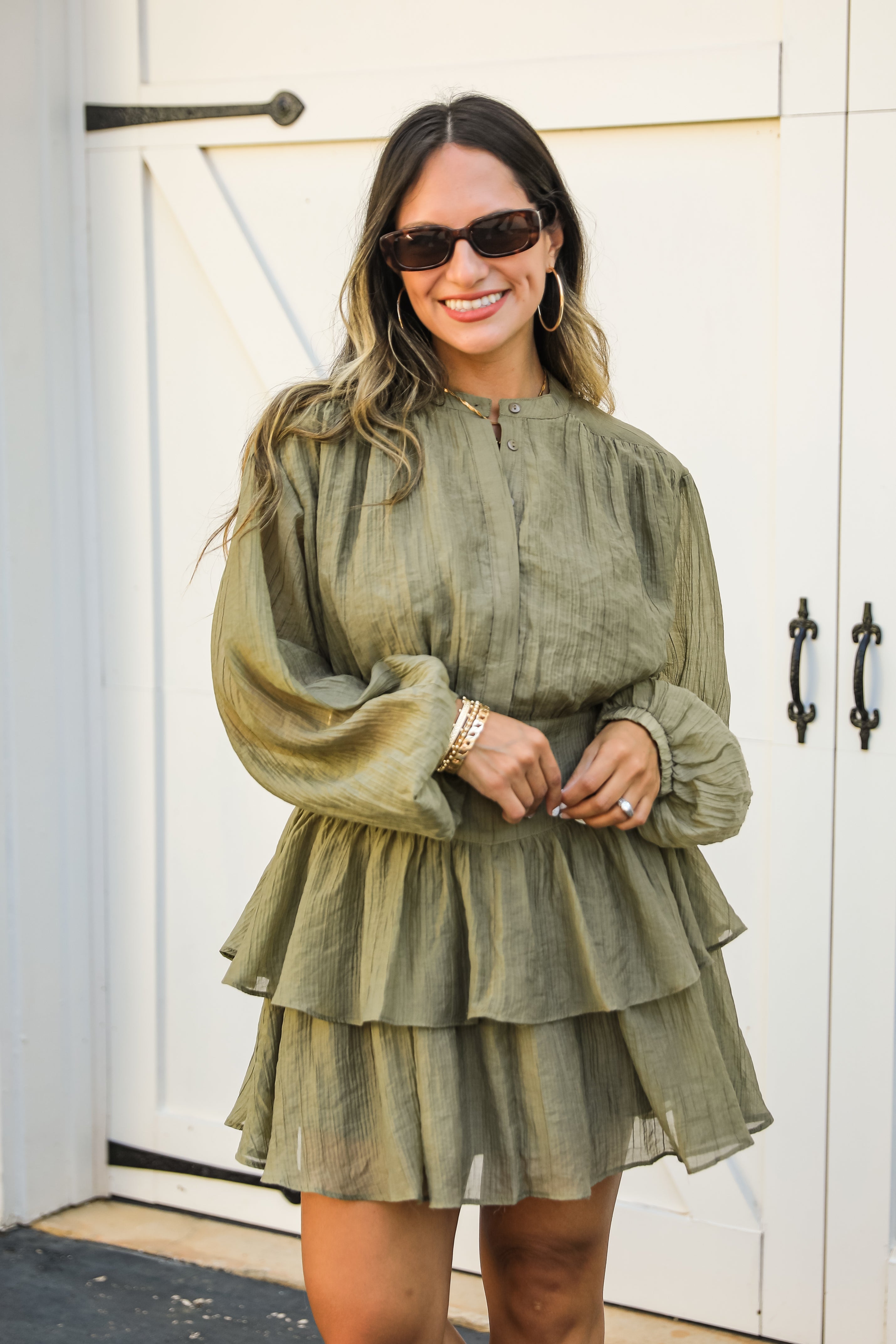 Woman wearing a green dress standing in front of a white door.