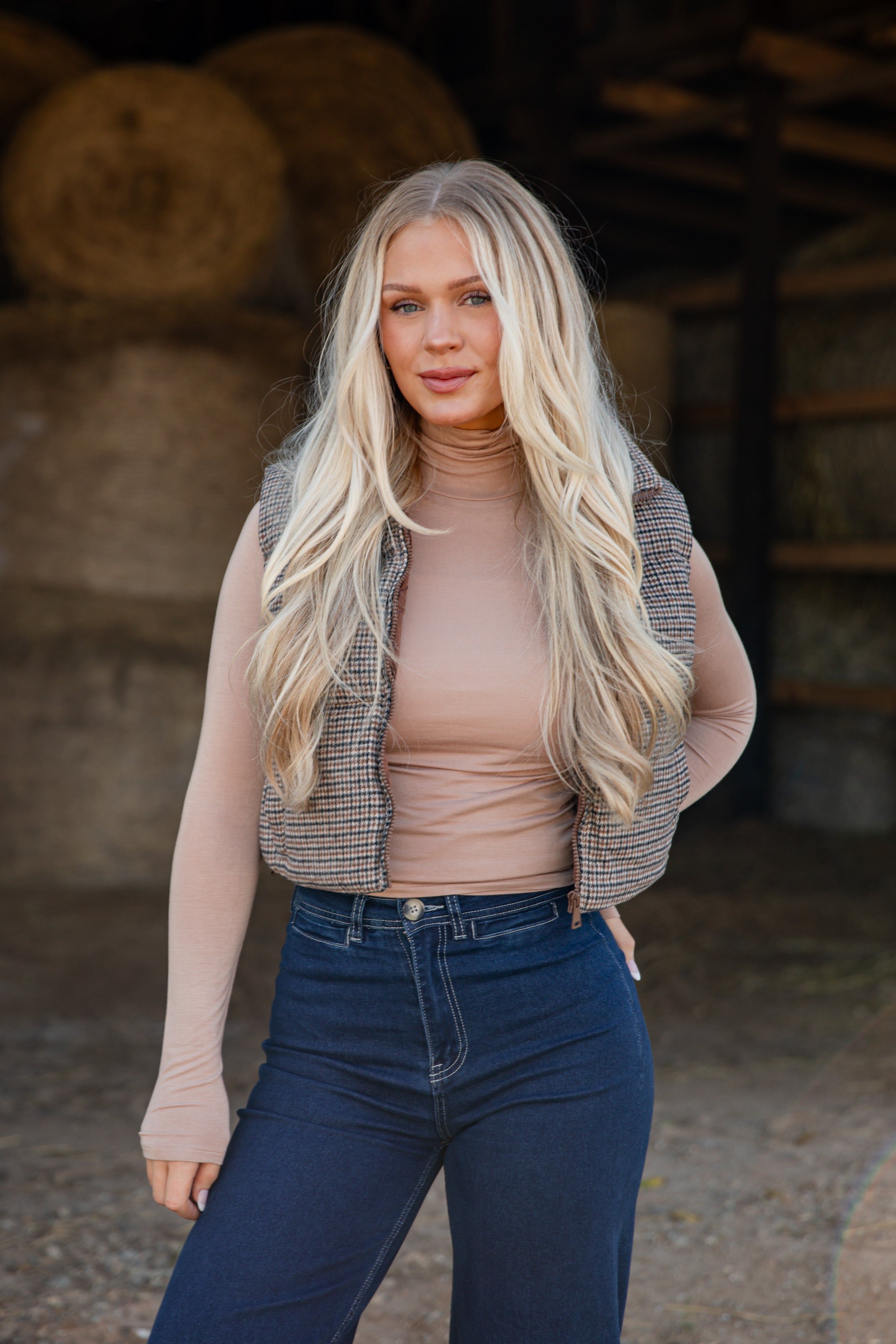 Woman standing in a barn with hay bales in the background
