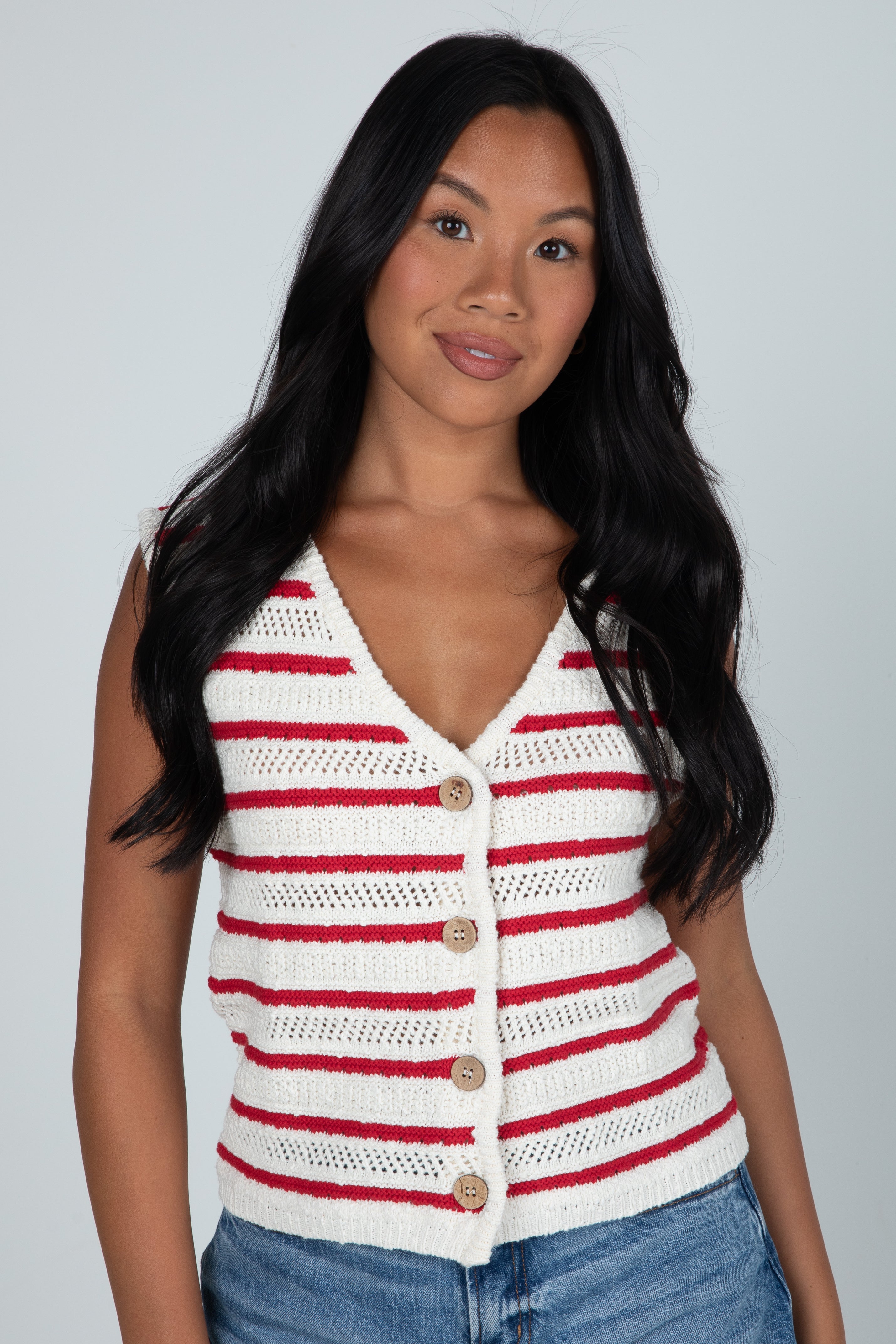 Woman wearing a red and white striped sleeveless cardigan against a plain background