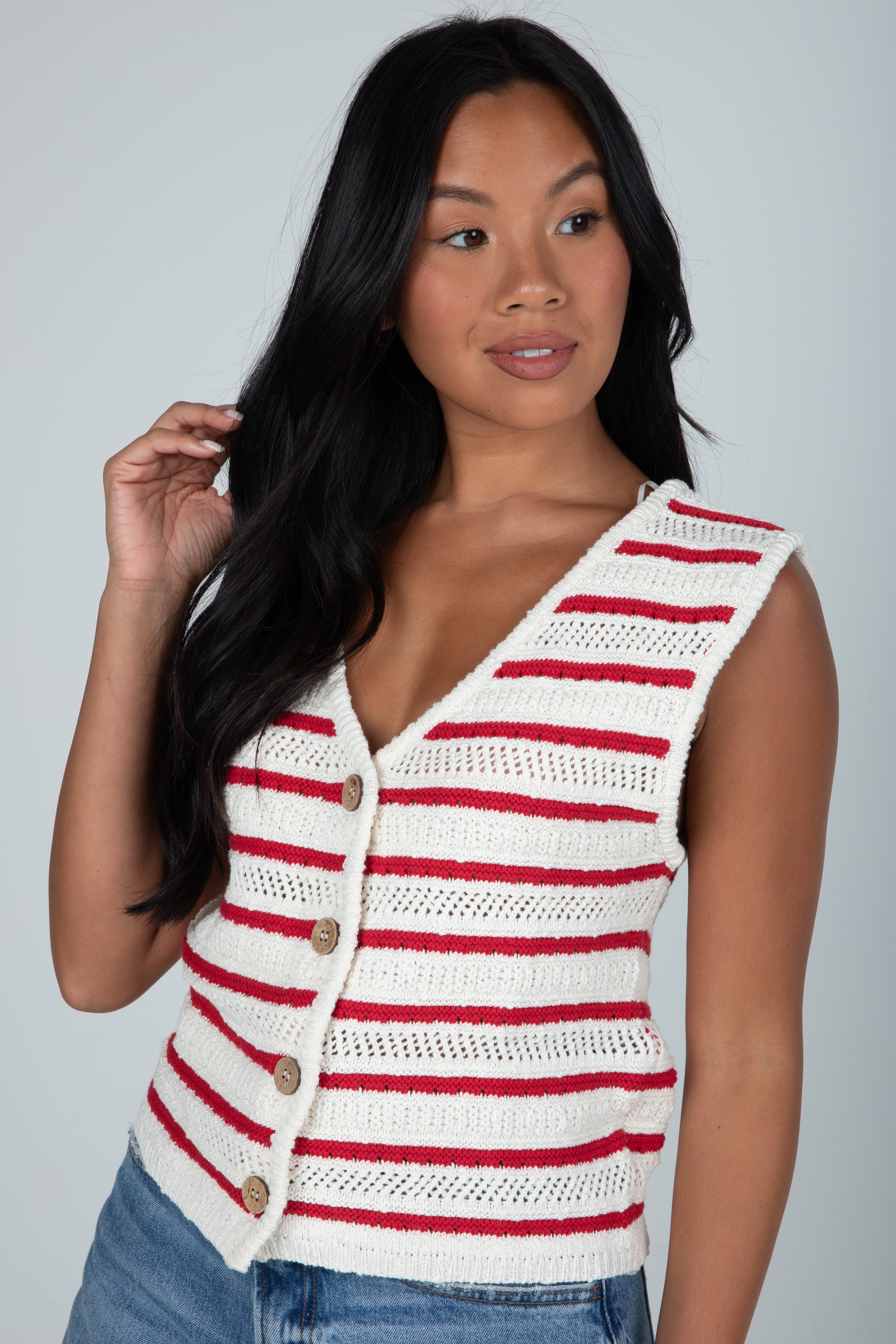 Woman wearing a red and white striped sleeveless knitted top against a gray background