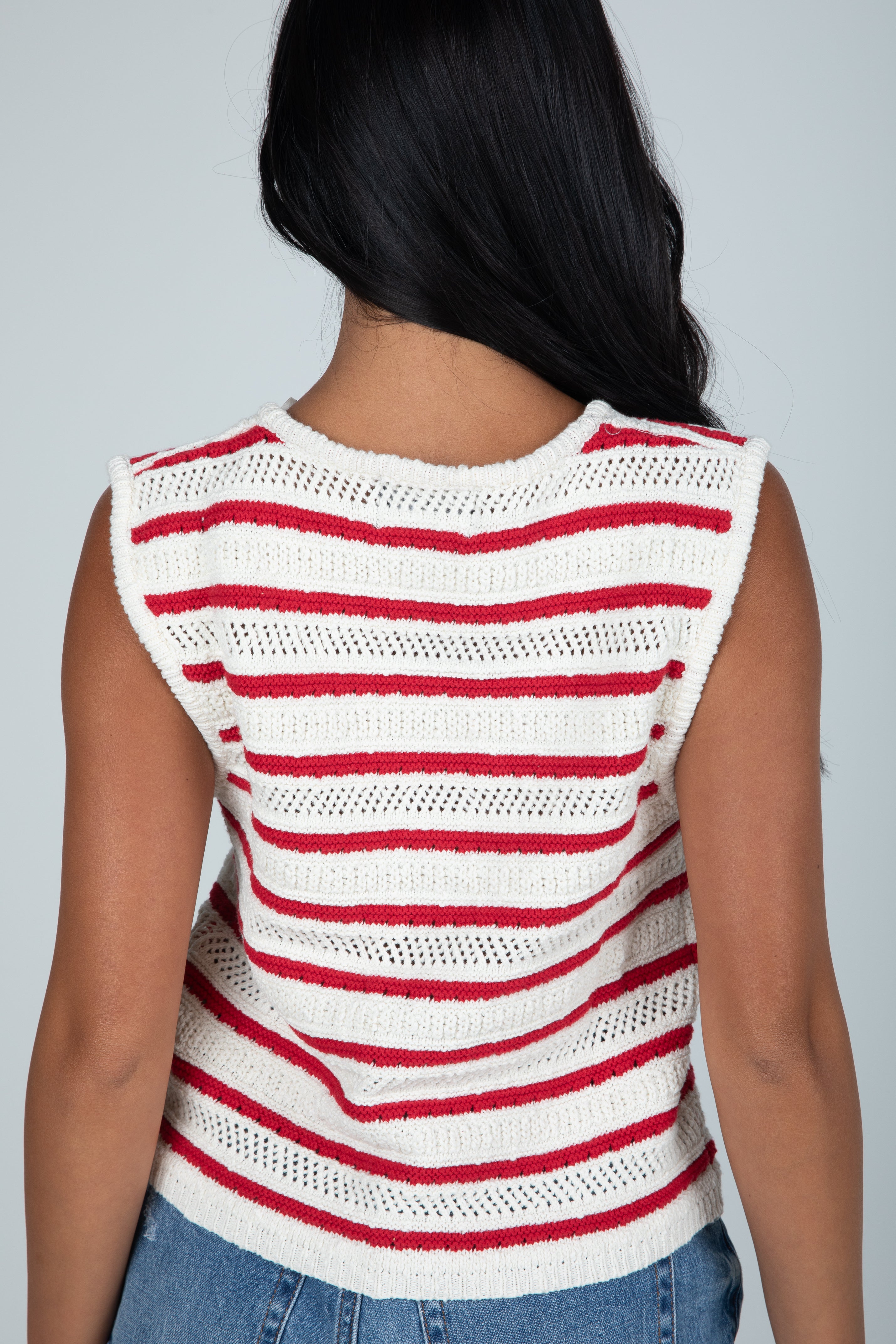 Person wearing a red and white striped sleeveless top against a gray background