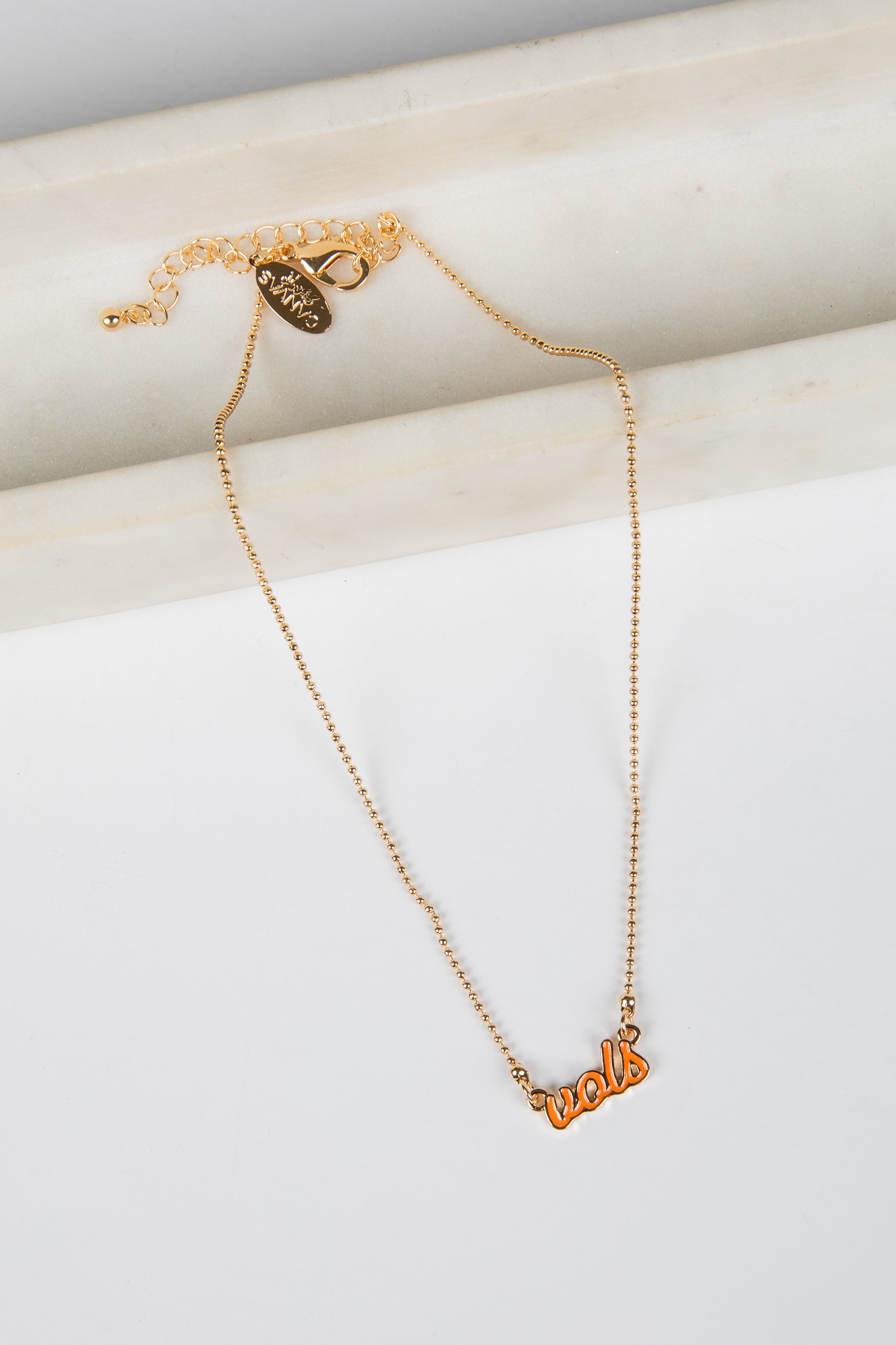 Gold necklace with a heart pendant on a white surface