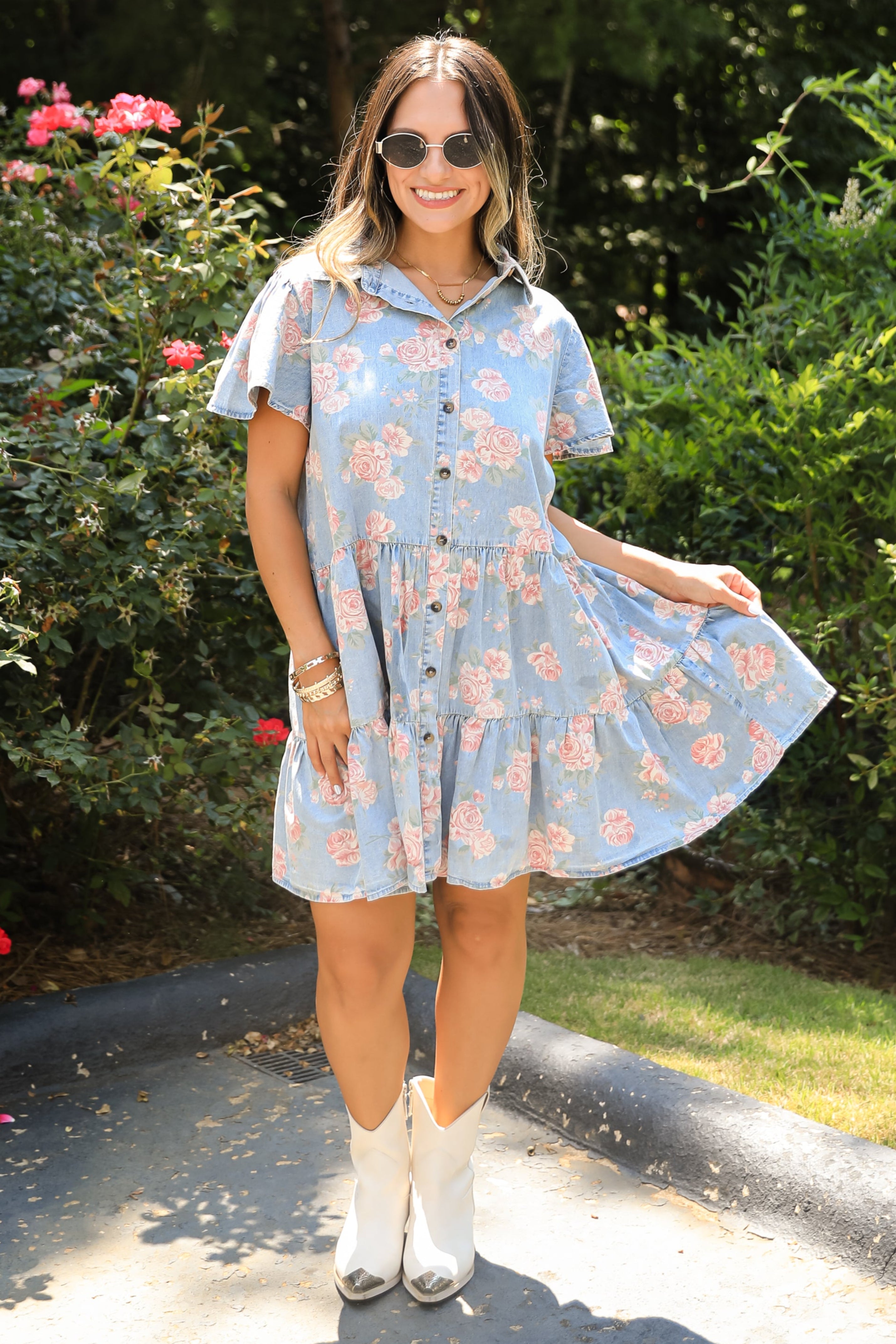 Woman in a floral dress standing outdoors with greenery in the background