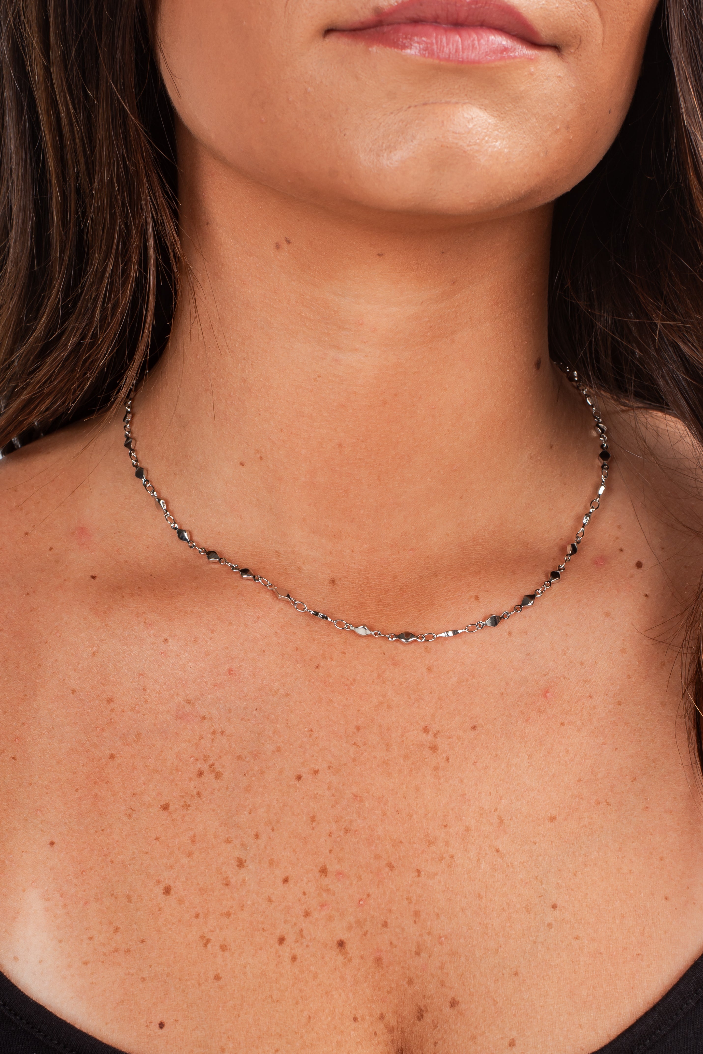 Close-up of a person wearing a delicate necklace with a blurred background