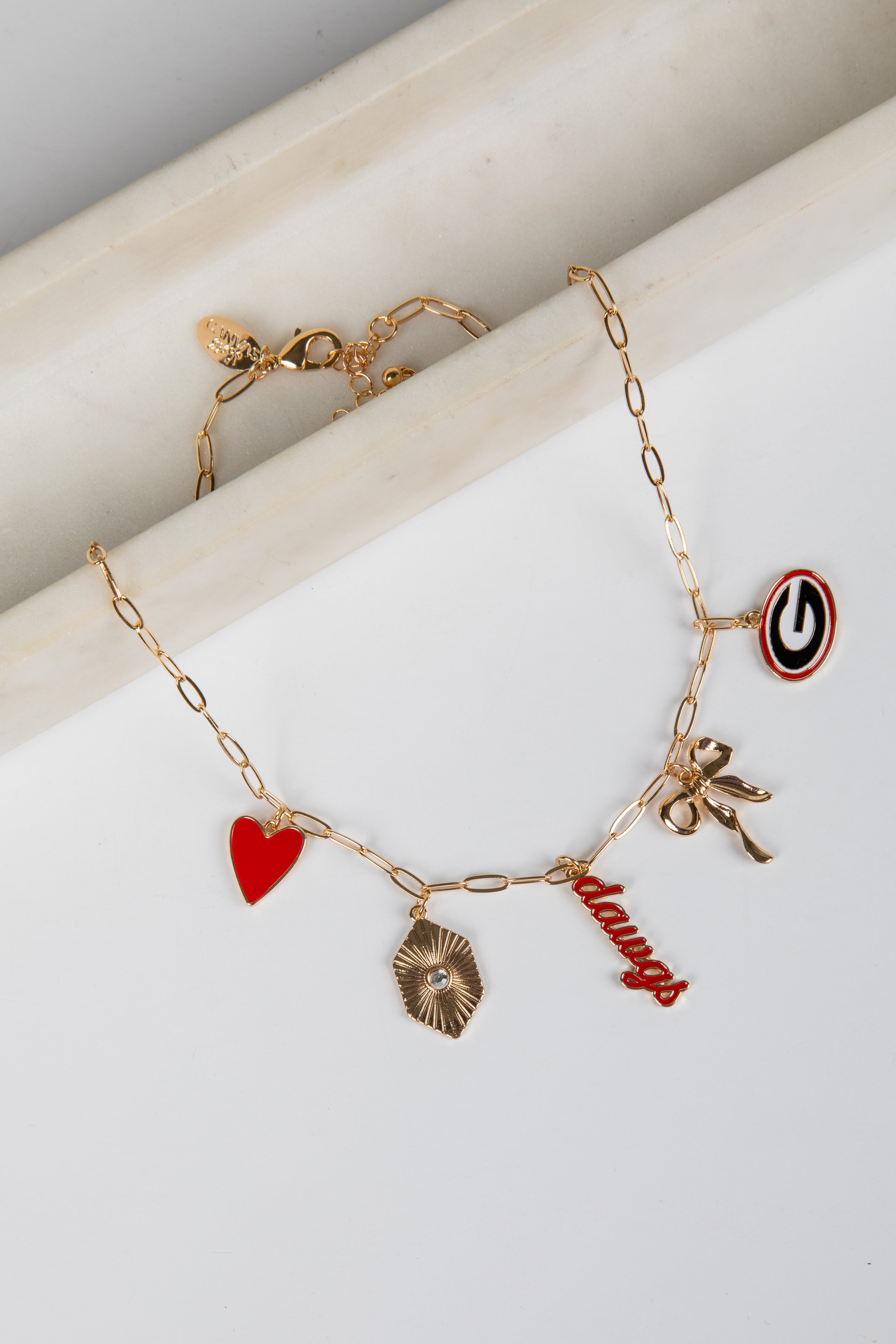 Gold bracelet with various charms on a white surface
