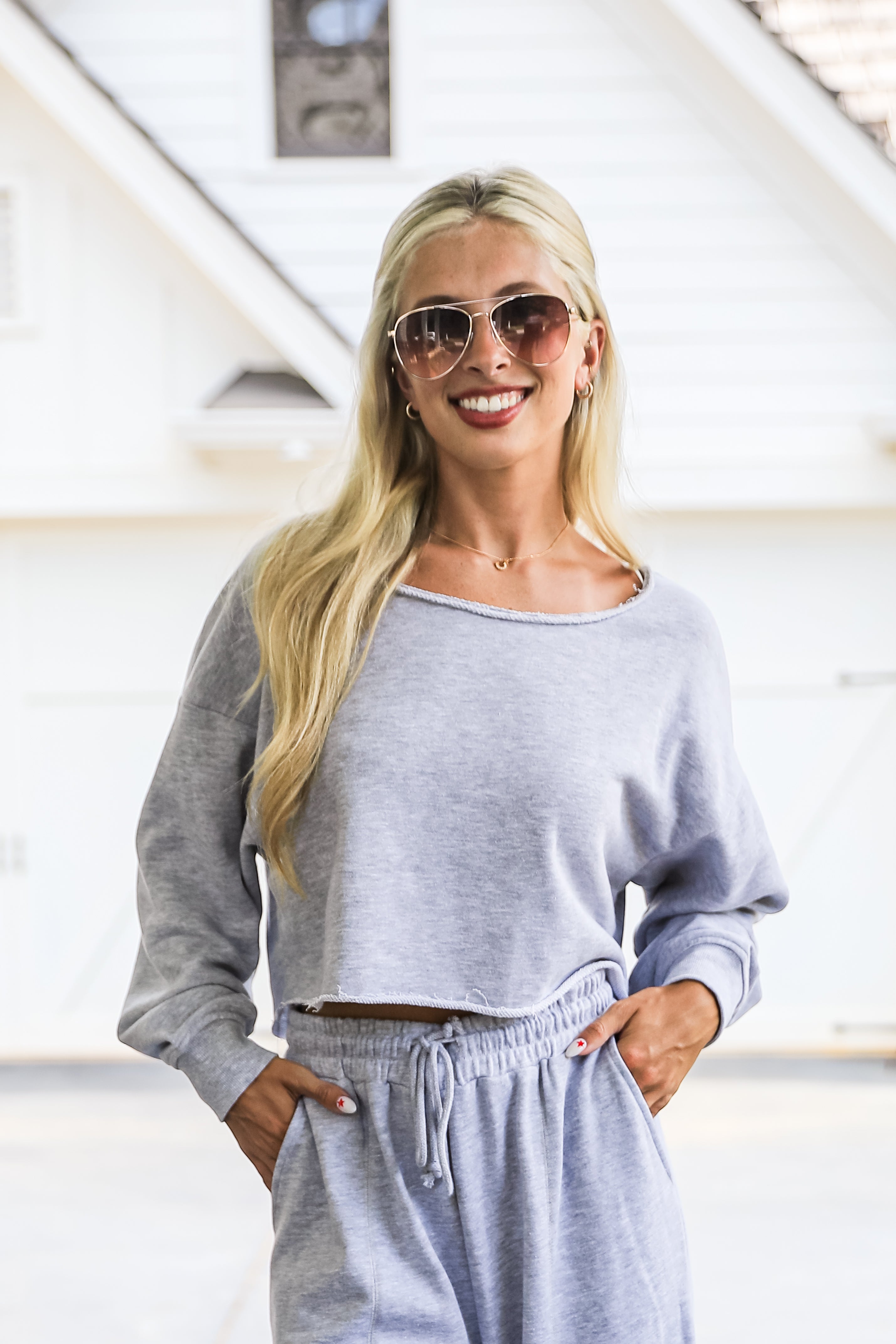 Woman wearing a gray outfit with sunglasses indoors