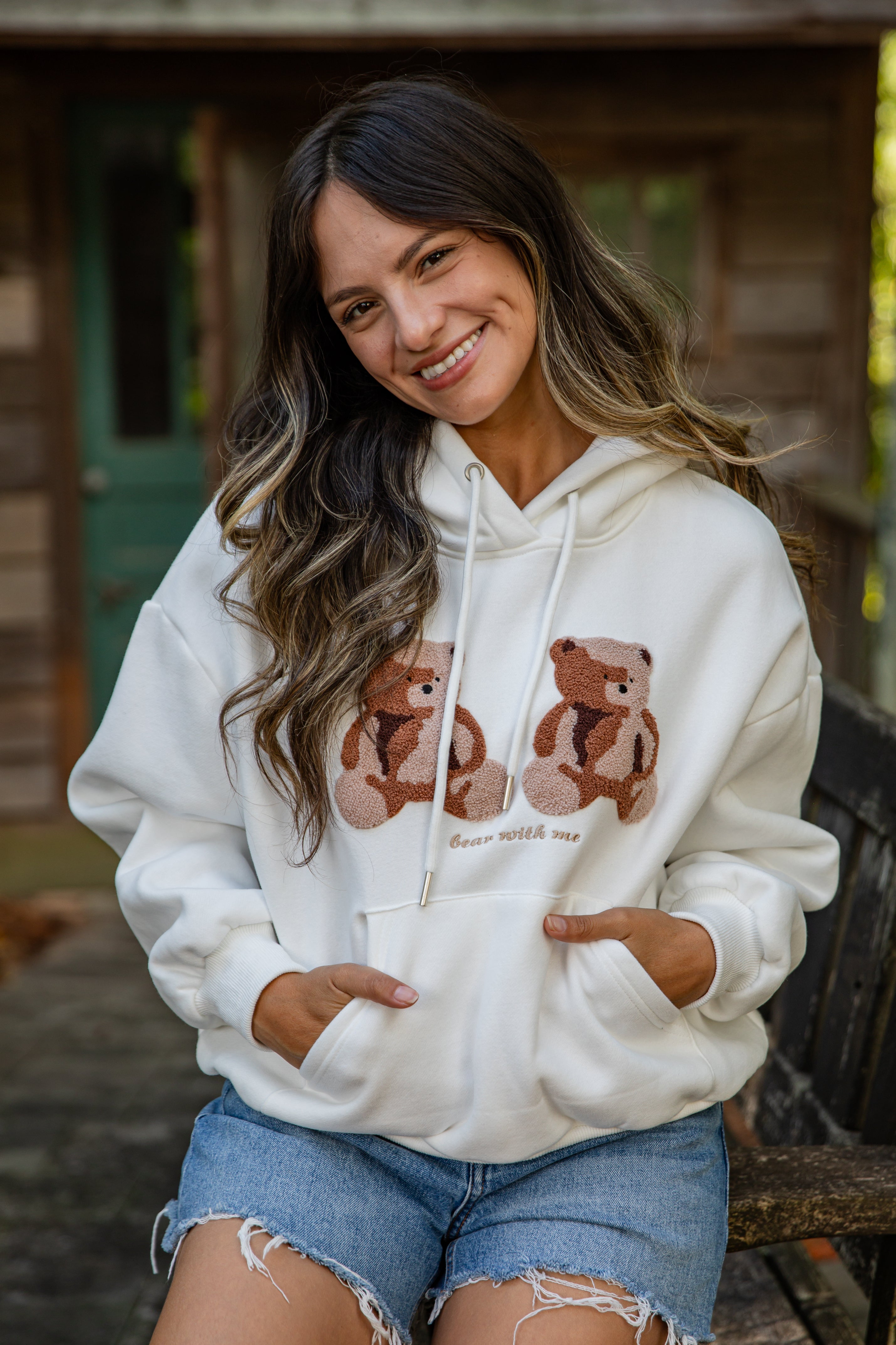 Woman wearing a white hoodie with teddy bear design outdoors