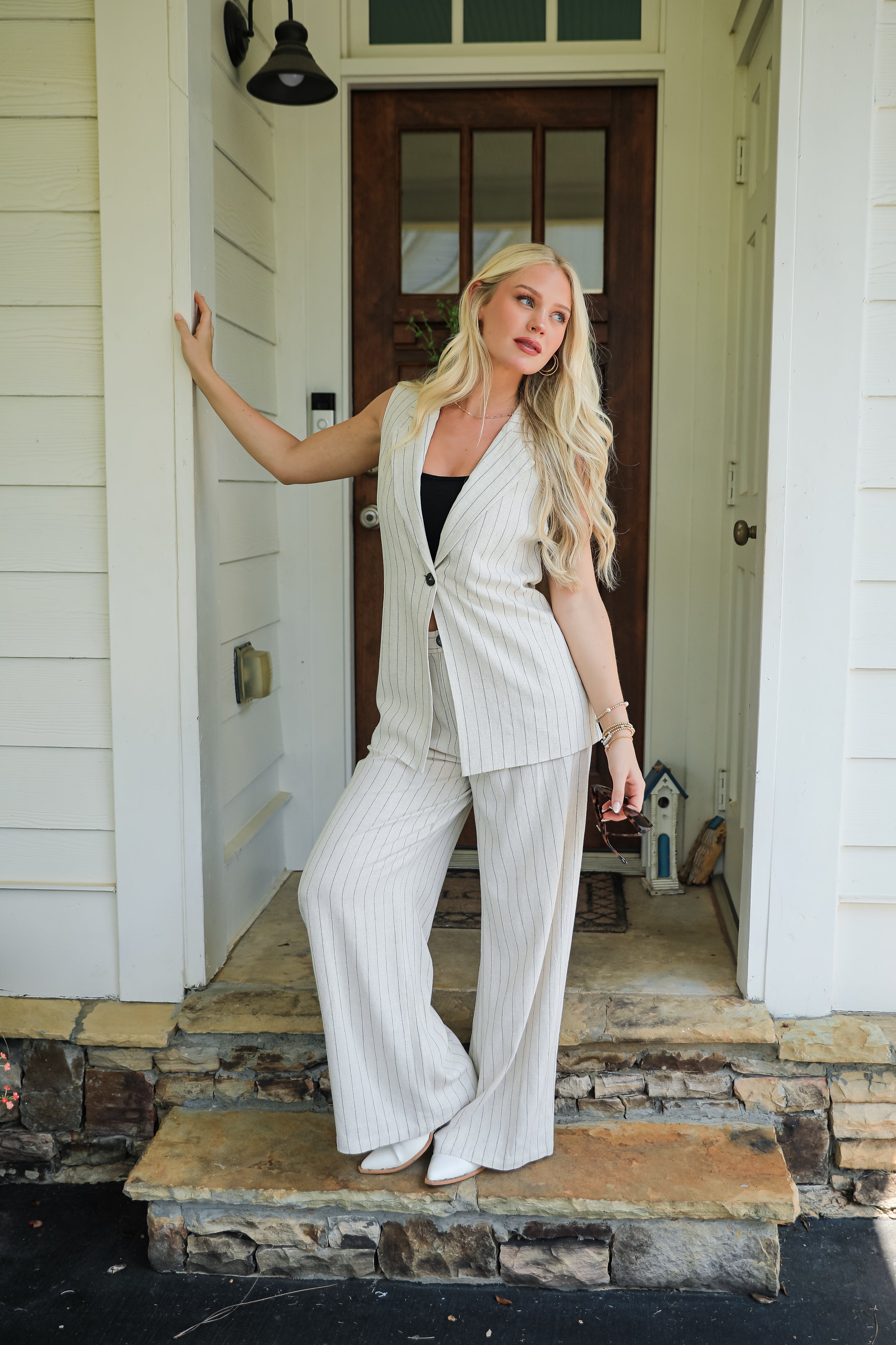 Woman in a white outfit standing on a porch