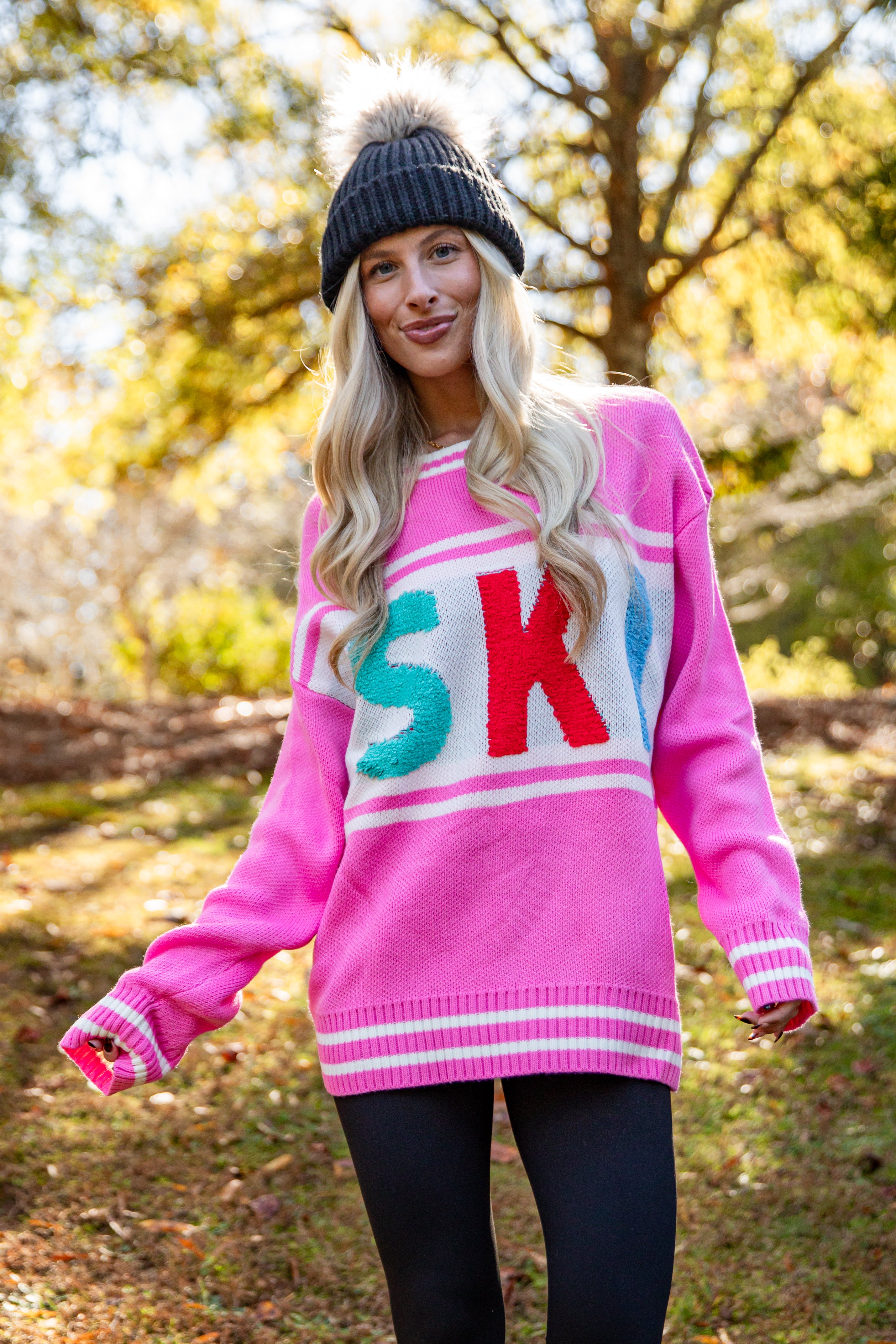 Person wearing a pink sweater with colorful letters outdoors