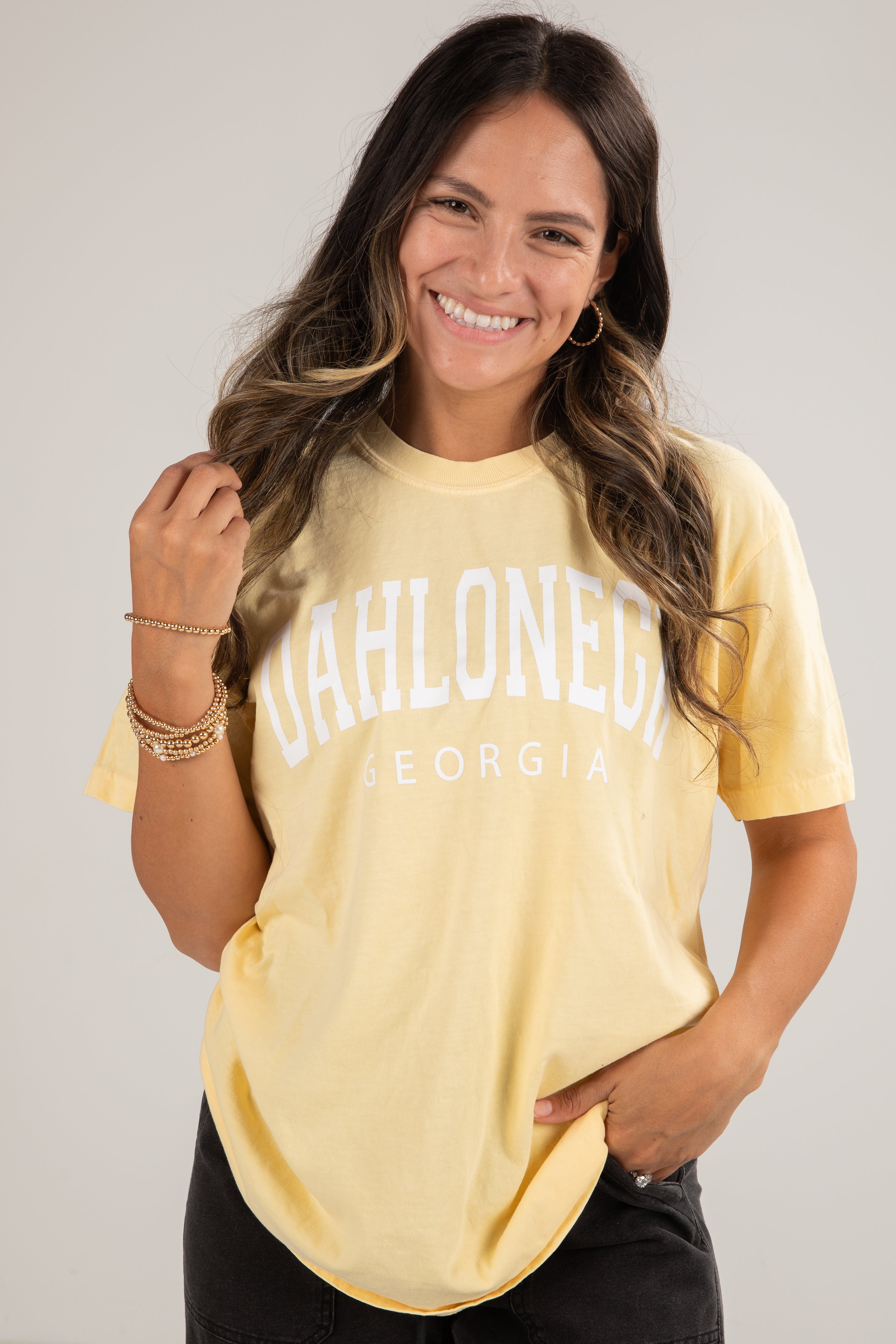 Woman wearing a yellow t-shirt with text, smiling against a plain background