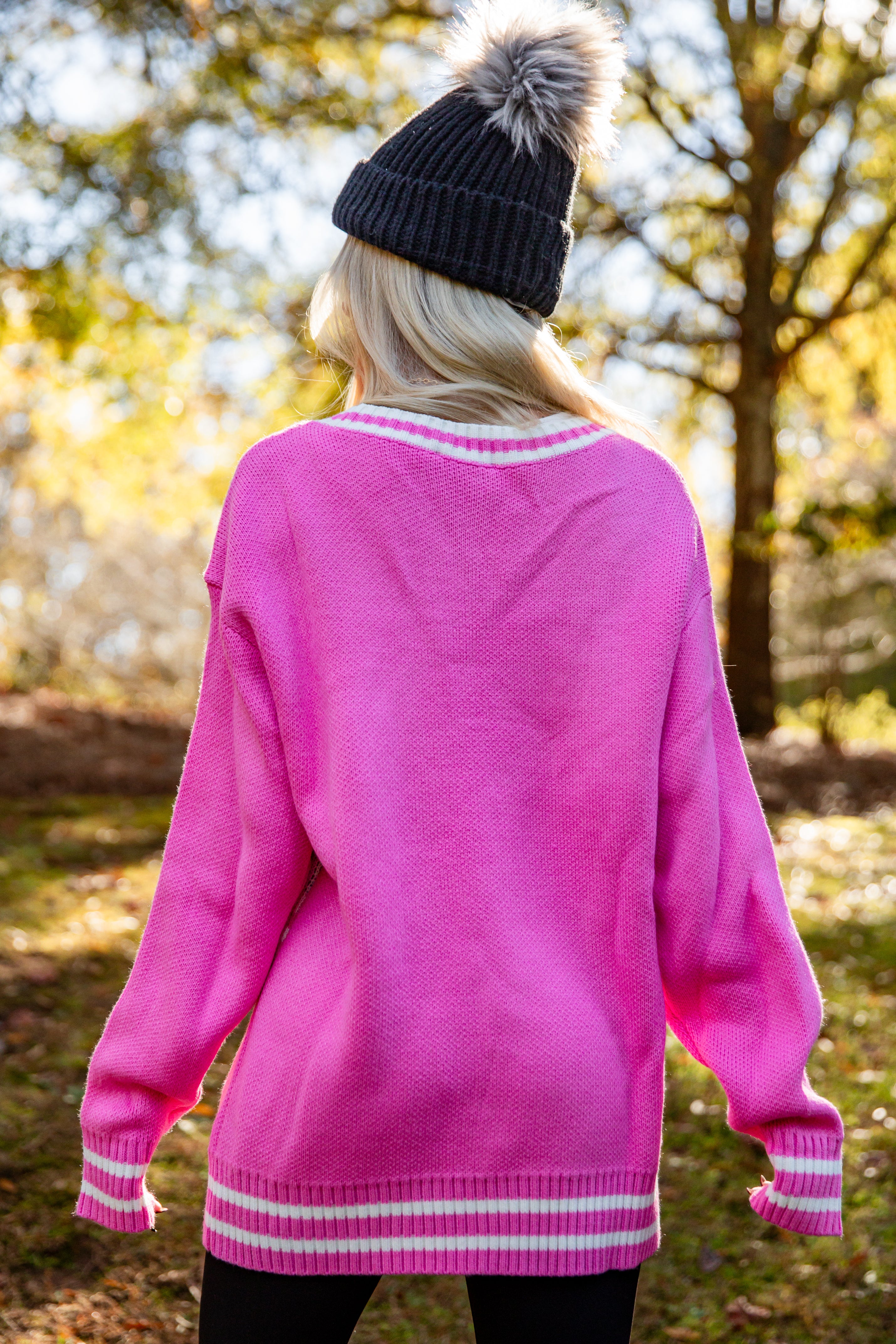Person wearing a pink sweater with white trim in an outdoor setting