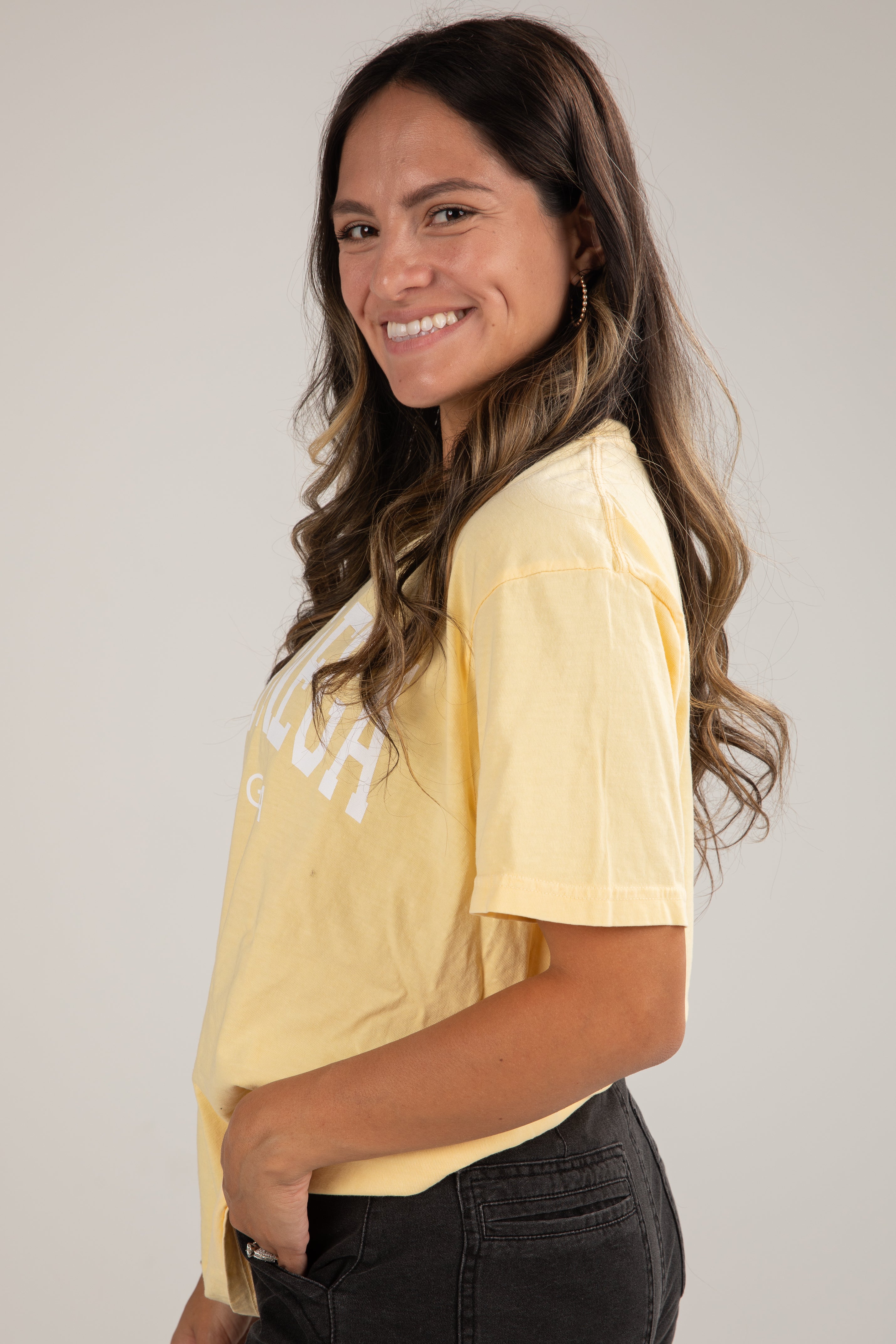 Woman wearing a yellow t-shirt with text on a plain background