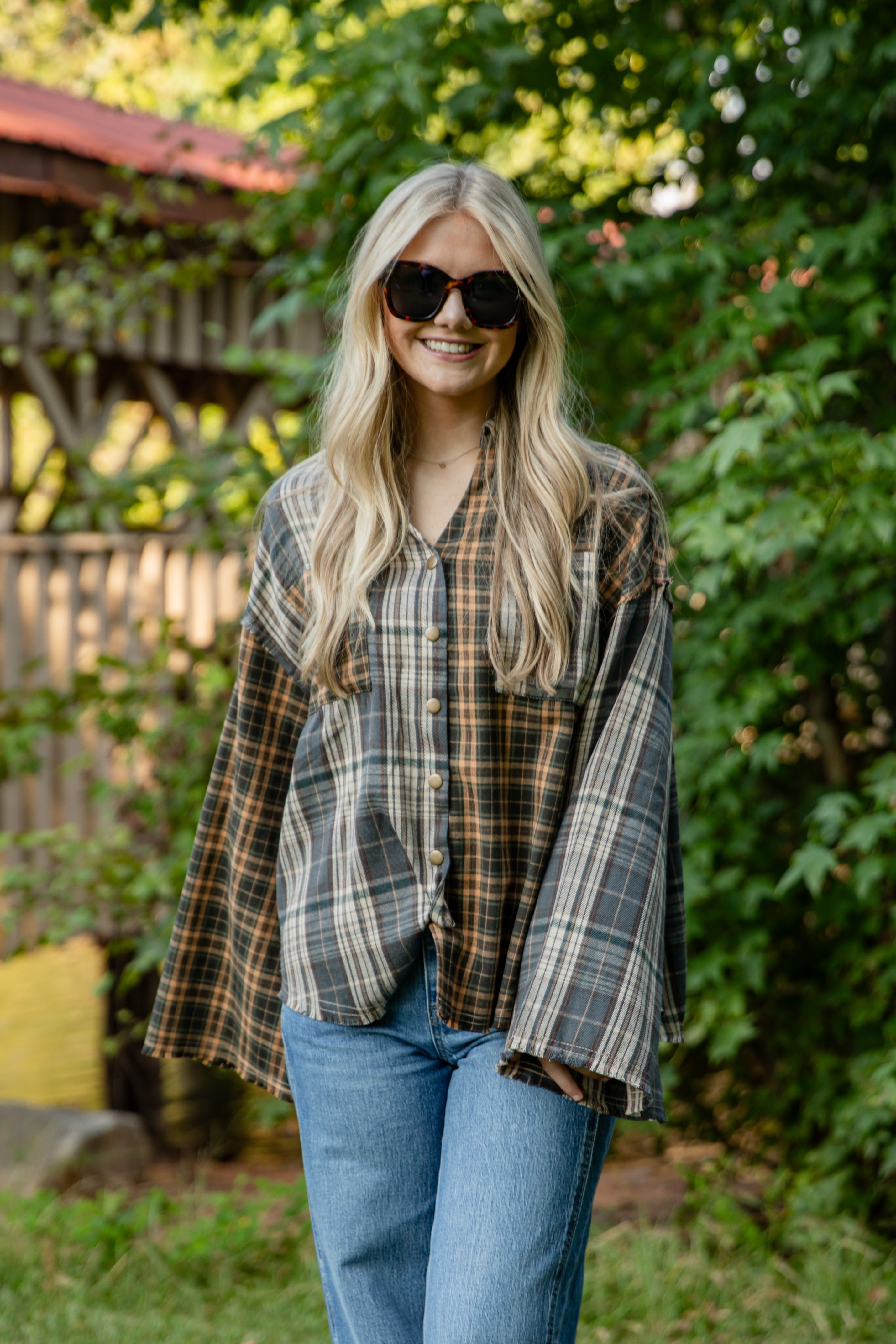 Woman wearing a plaid shirt and sunglasses outdoors