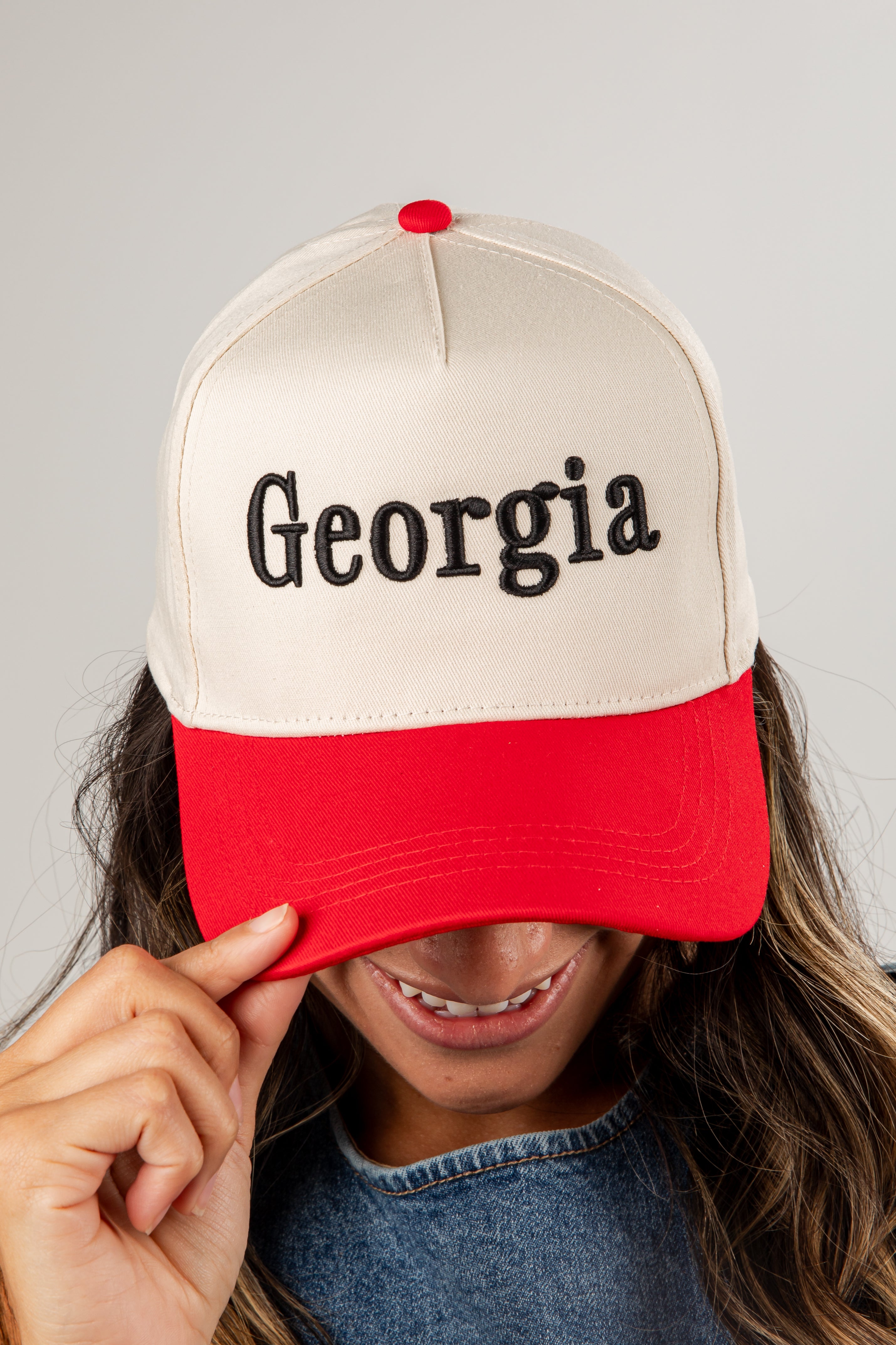 Person wearing a beige and red cap with &