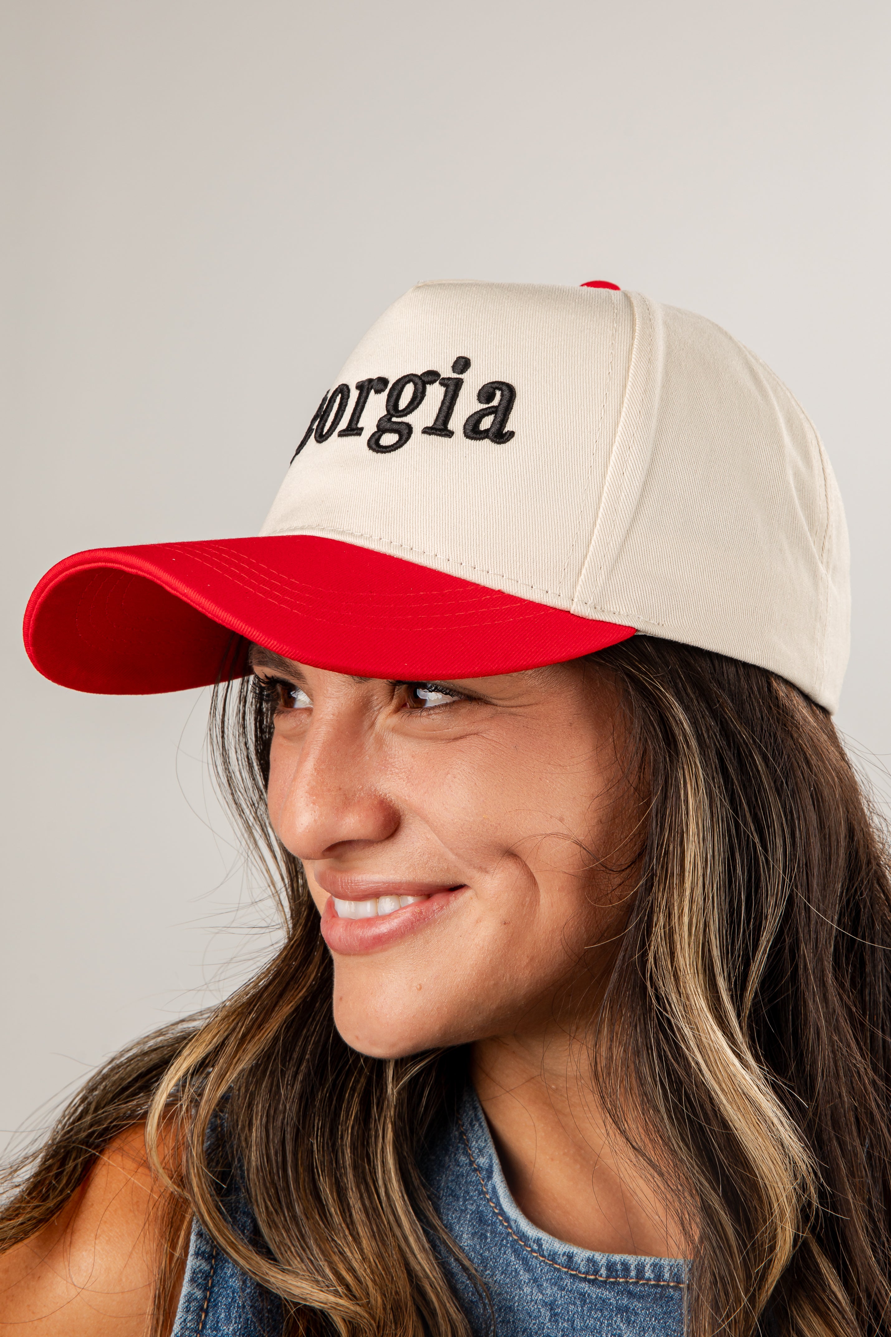 Woman wearing a beige and red cap with &