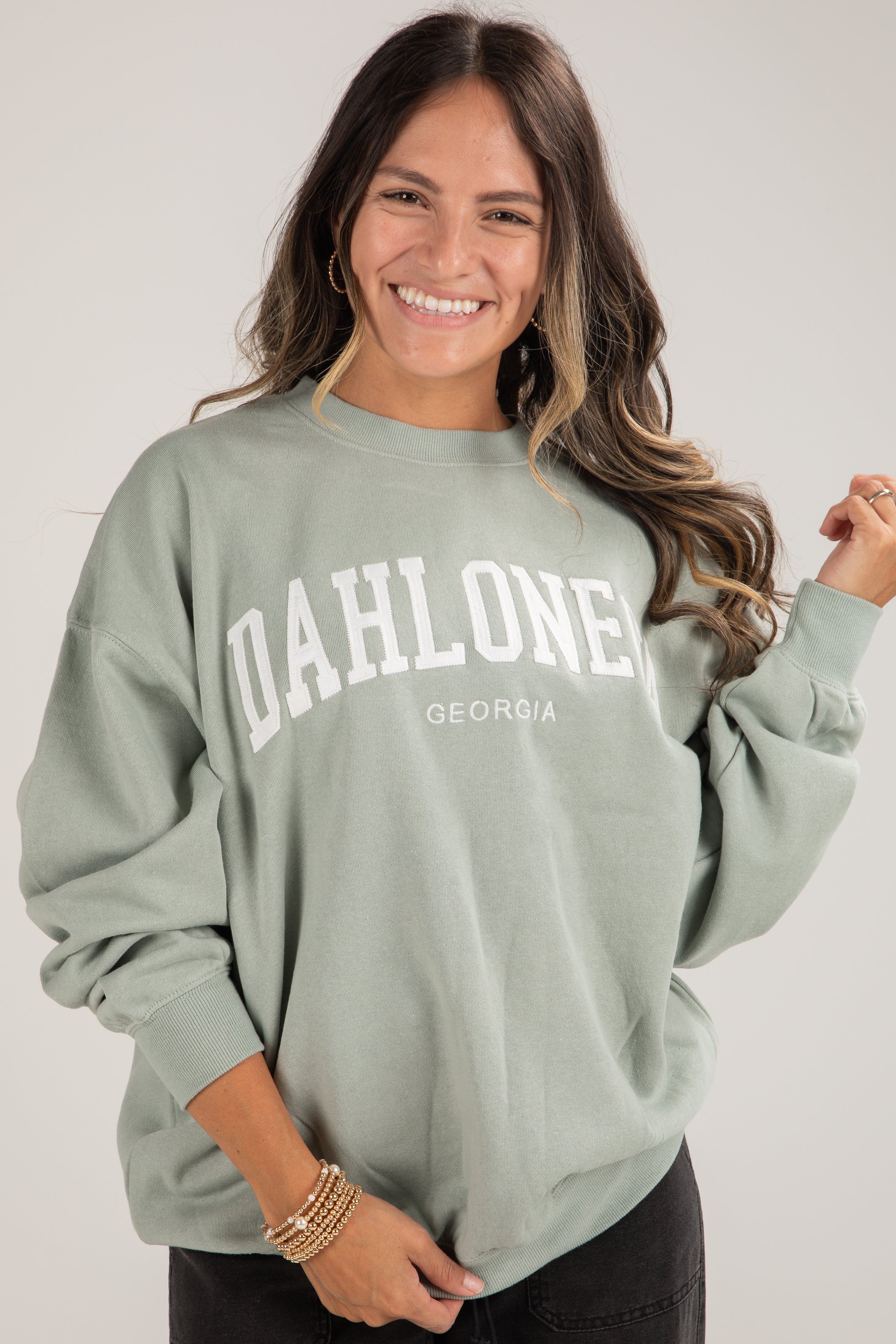 Woman wearing a light green sweatshirt with &