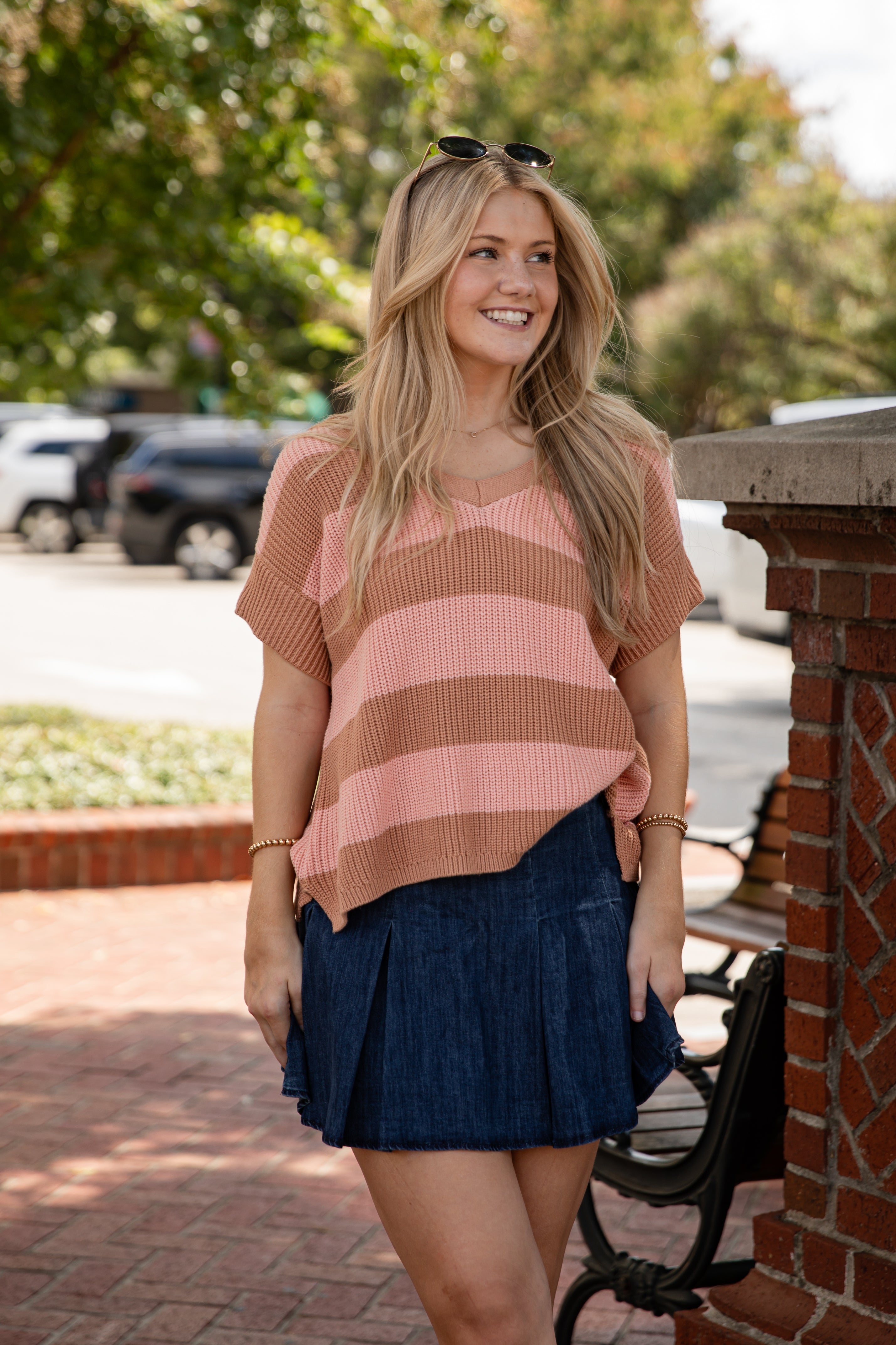 Woman wearing a striped sweater and denim skirt standing outdoors.