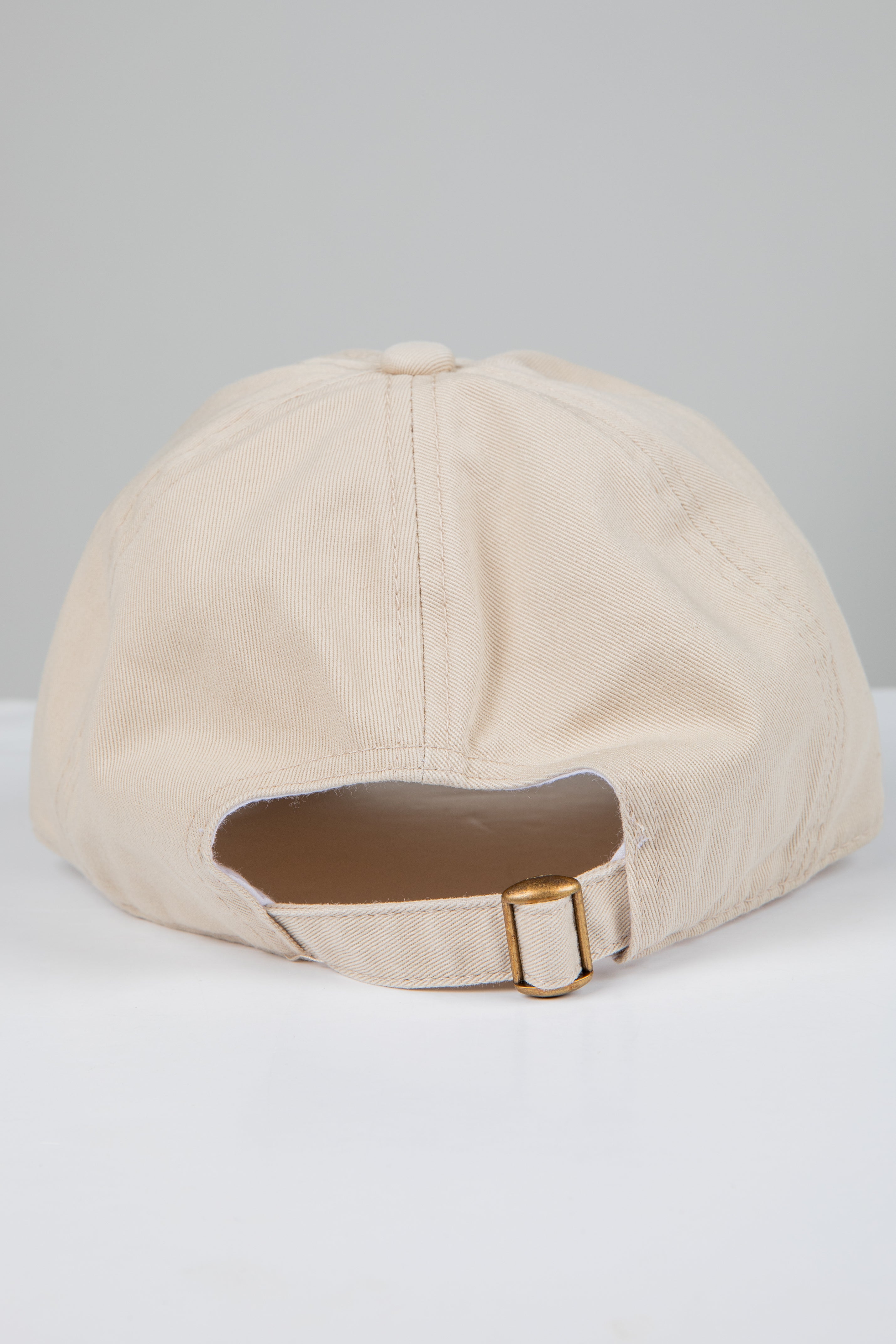 Beige baseball cap with a brown patch on a light gray background