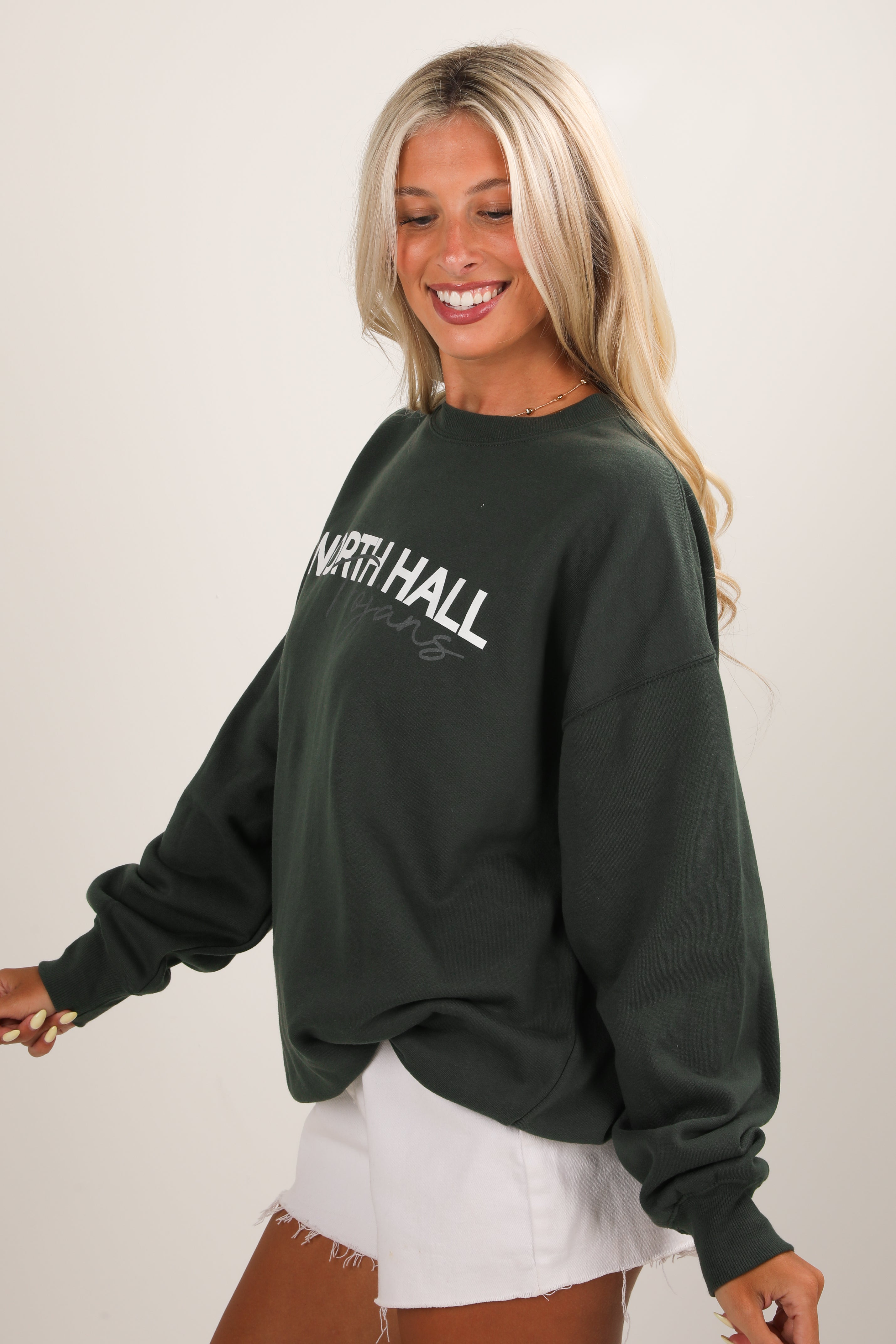 Woman wearing a dark green sweatshirt with &