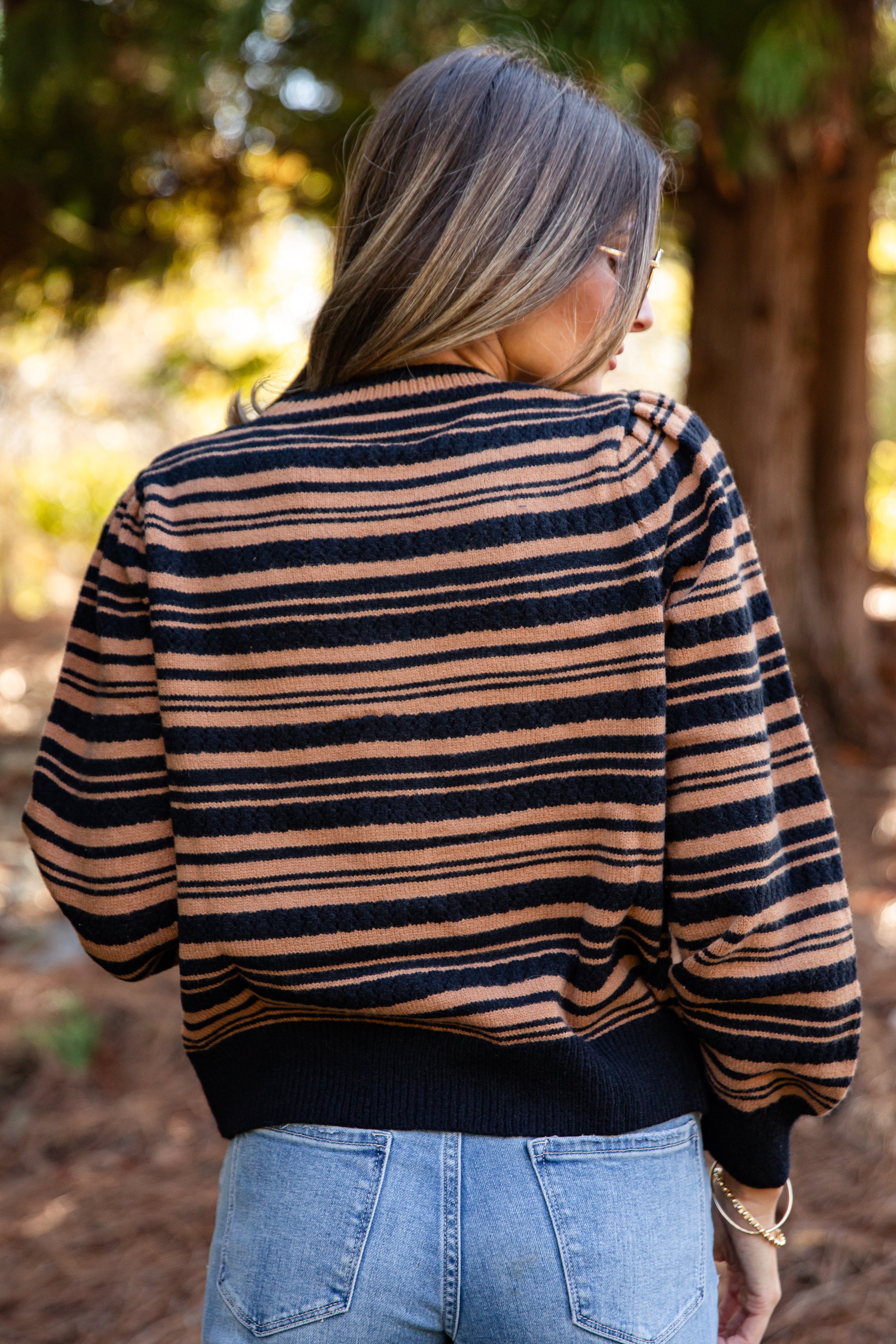 Person wearing a striped sweater and jeans in an outdoor setting