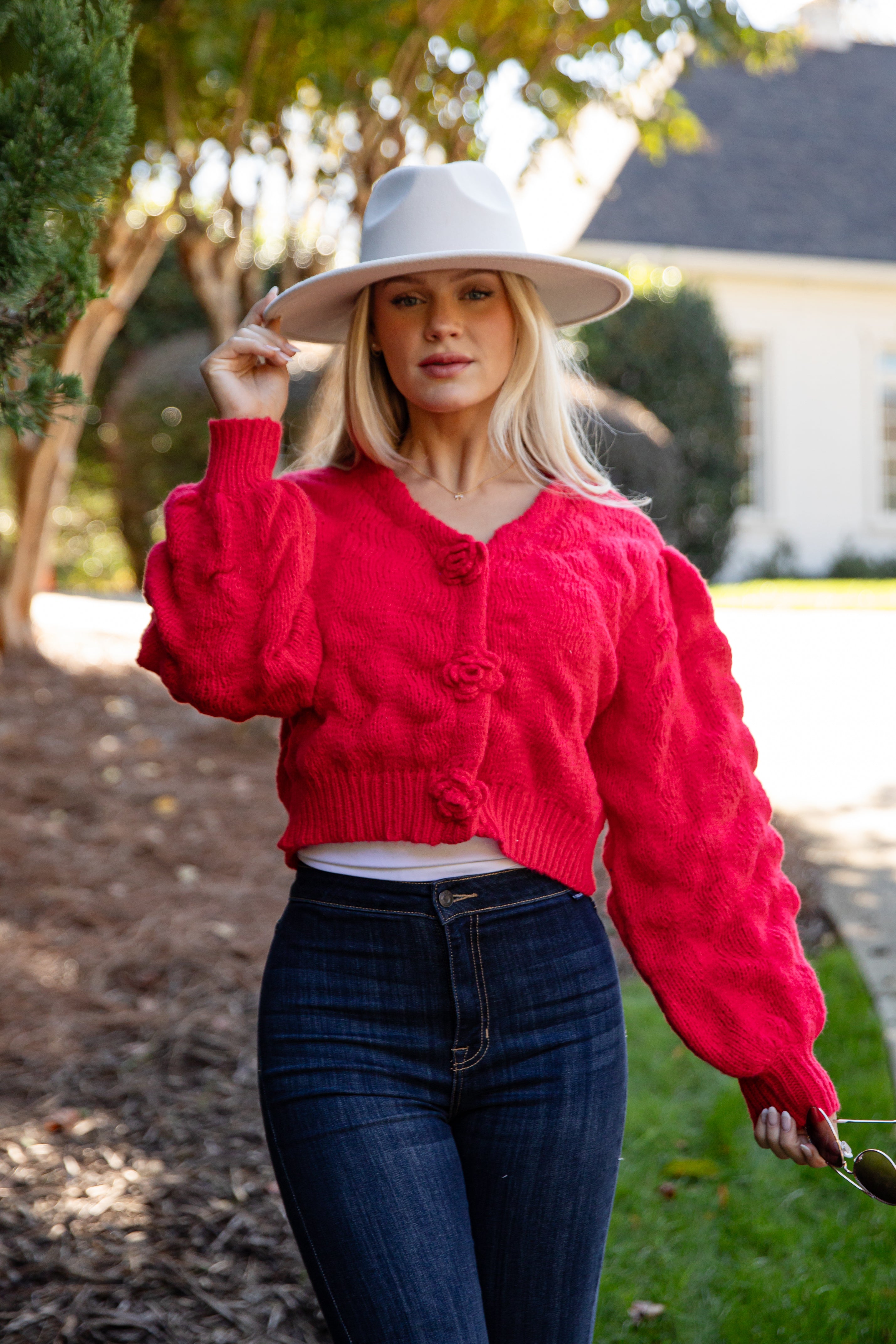 Woman wearing a red cardigan and white hat outdoors