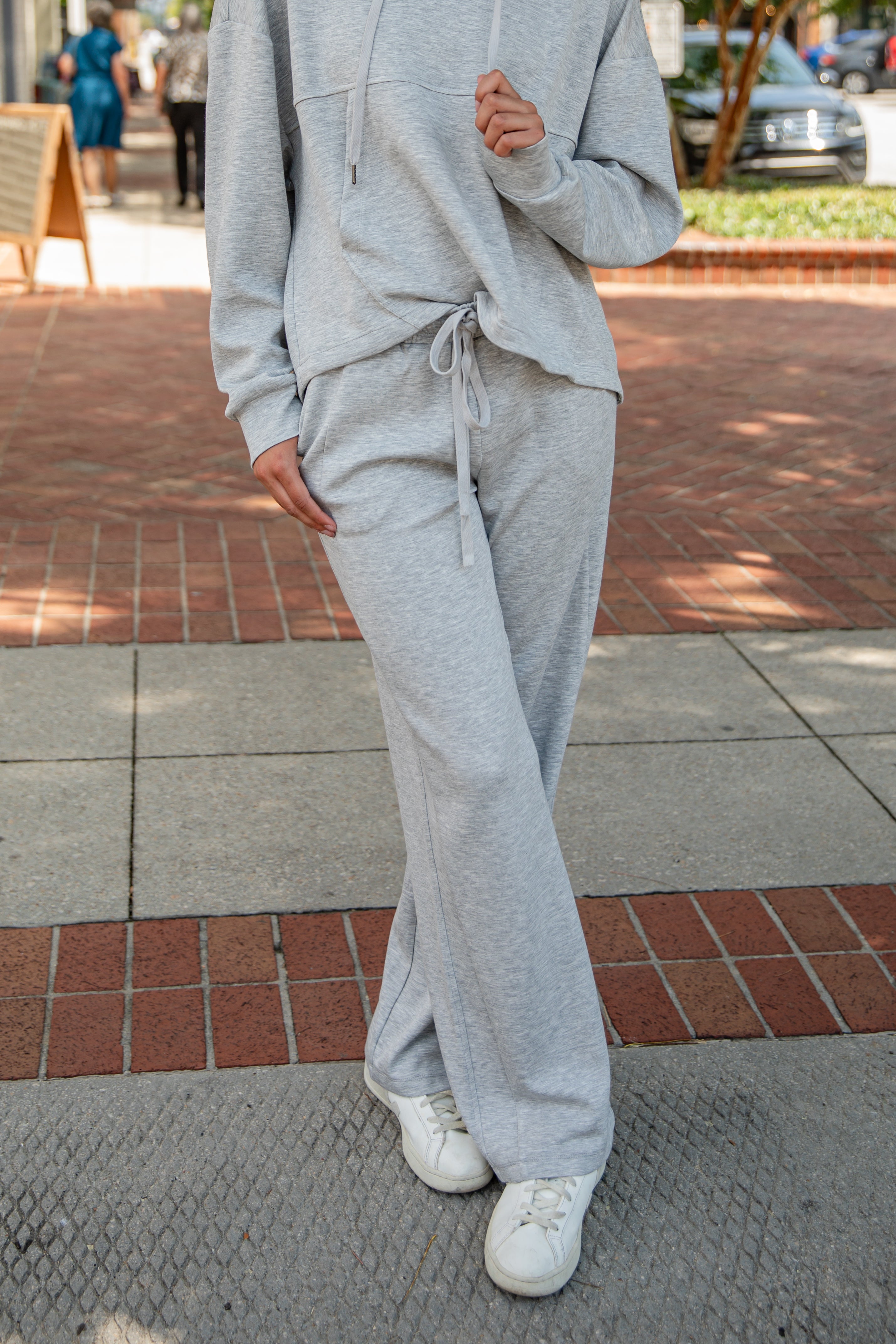 Person wearing a gray tracksuit on a sidewalk