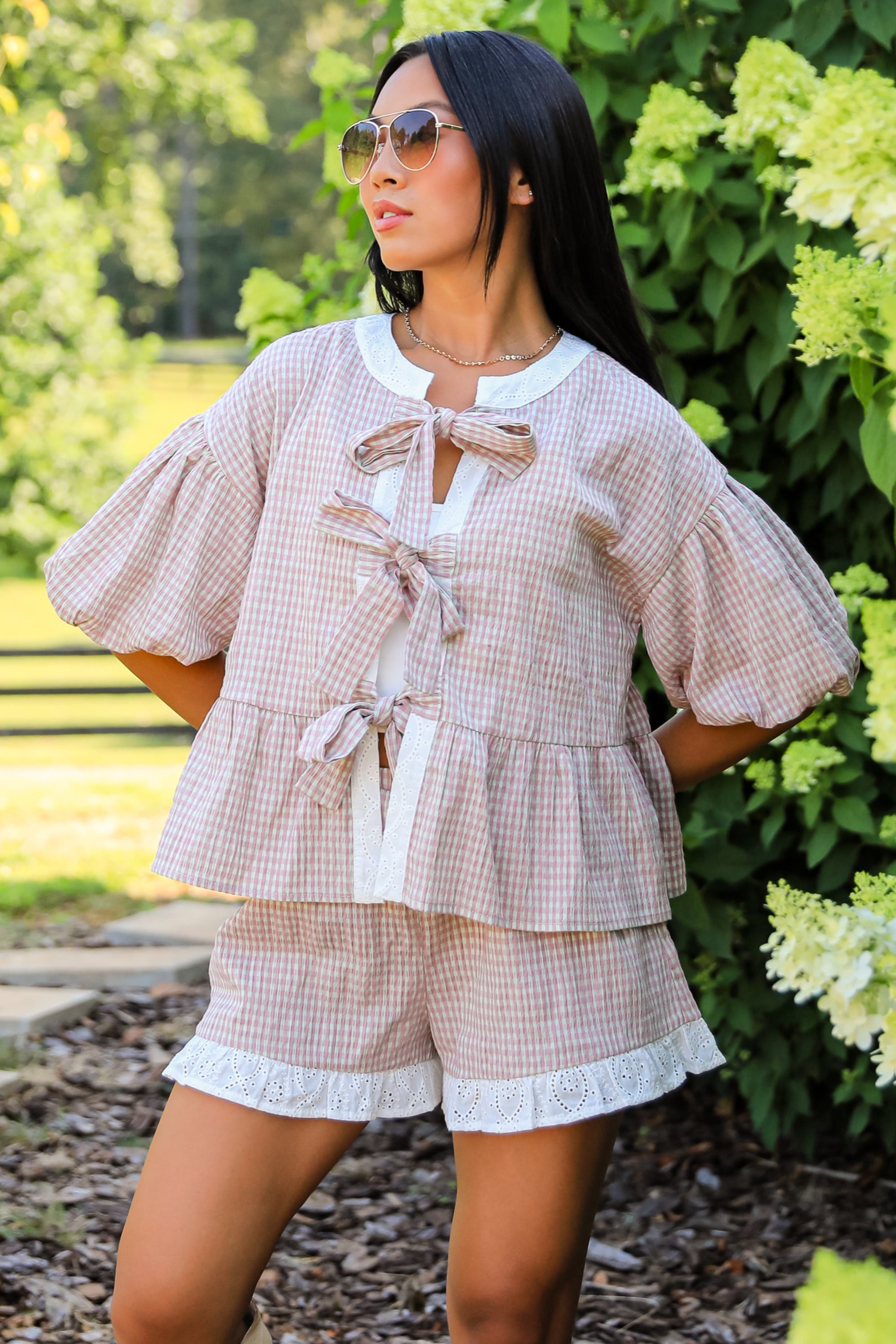 Woman in a light outfit standing on a stone path with greenery around