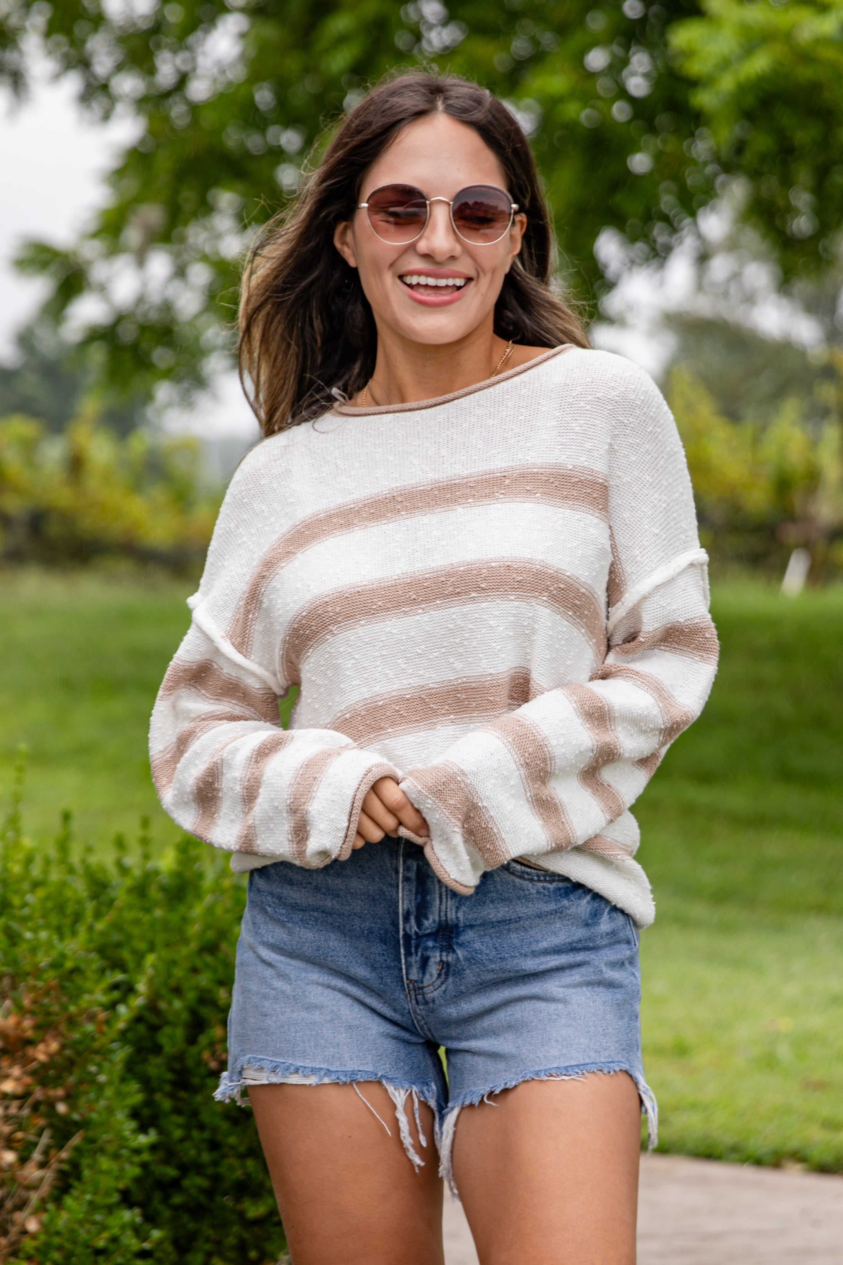Woman wearing a striped sweater and denim shorts outdoors