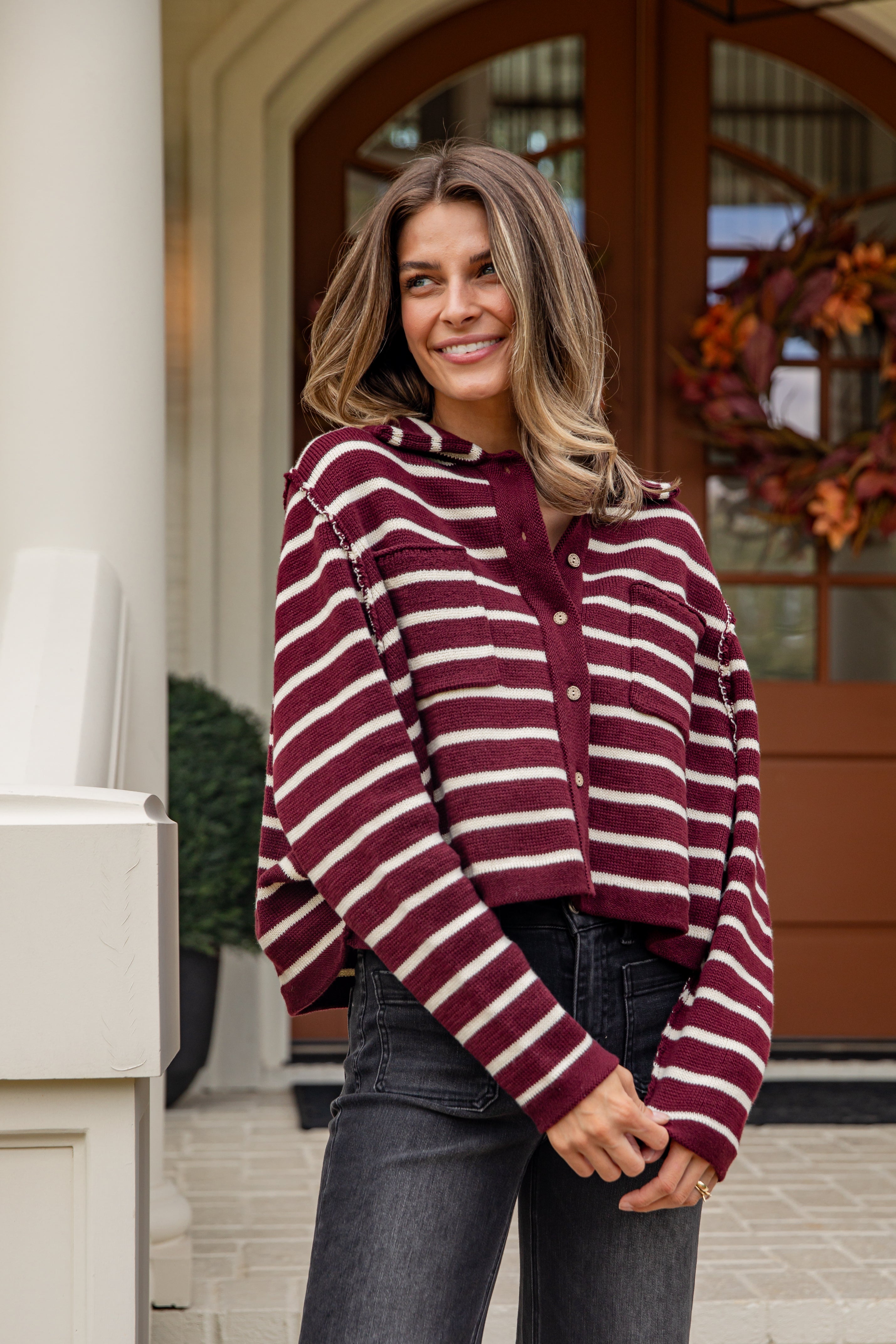 Woman wearing a maroon and white striped sweater standing outdoors.