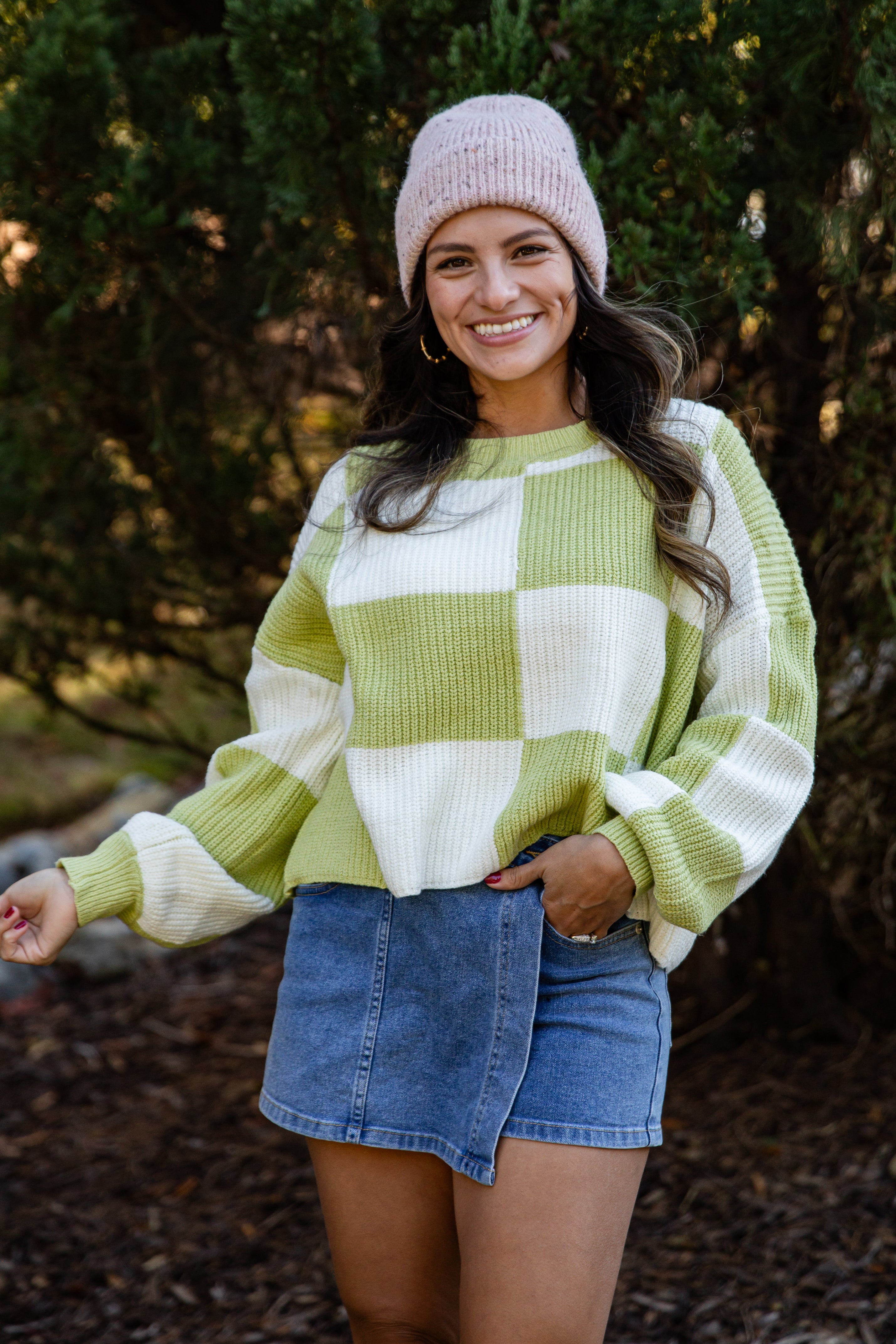Woman wearing a checkered sweater and denim skirt outdoors