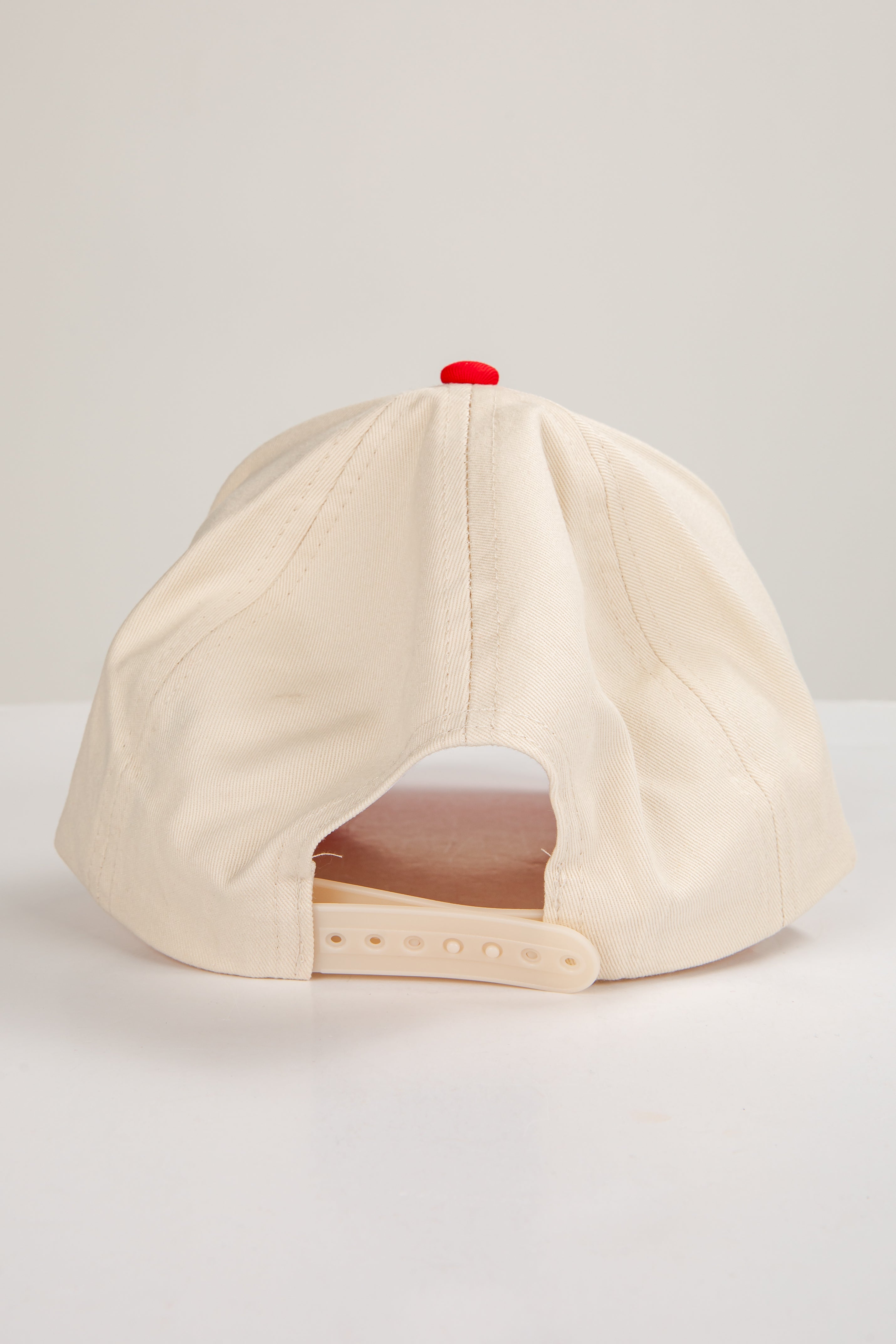 Beige baseball cap with a red button on a light gray background