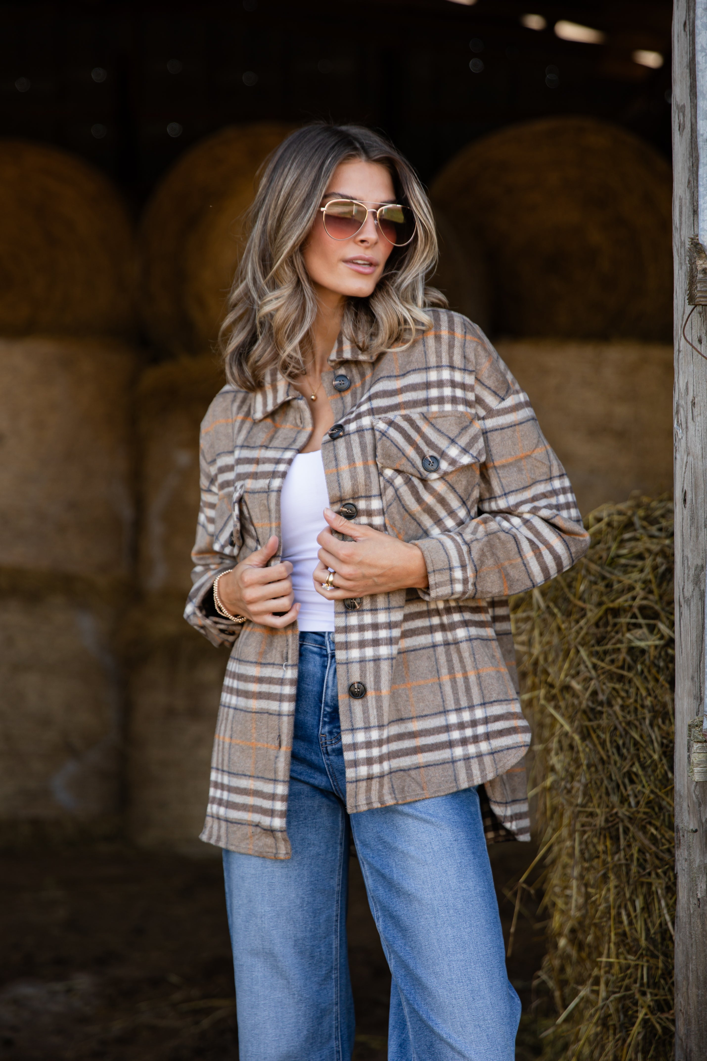 Woman wearing a plaid jacket and sunglasses in a barn setting