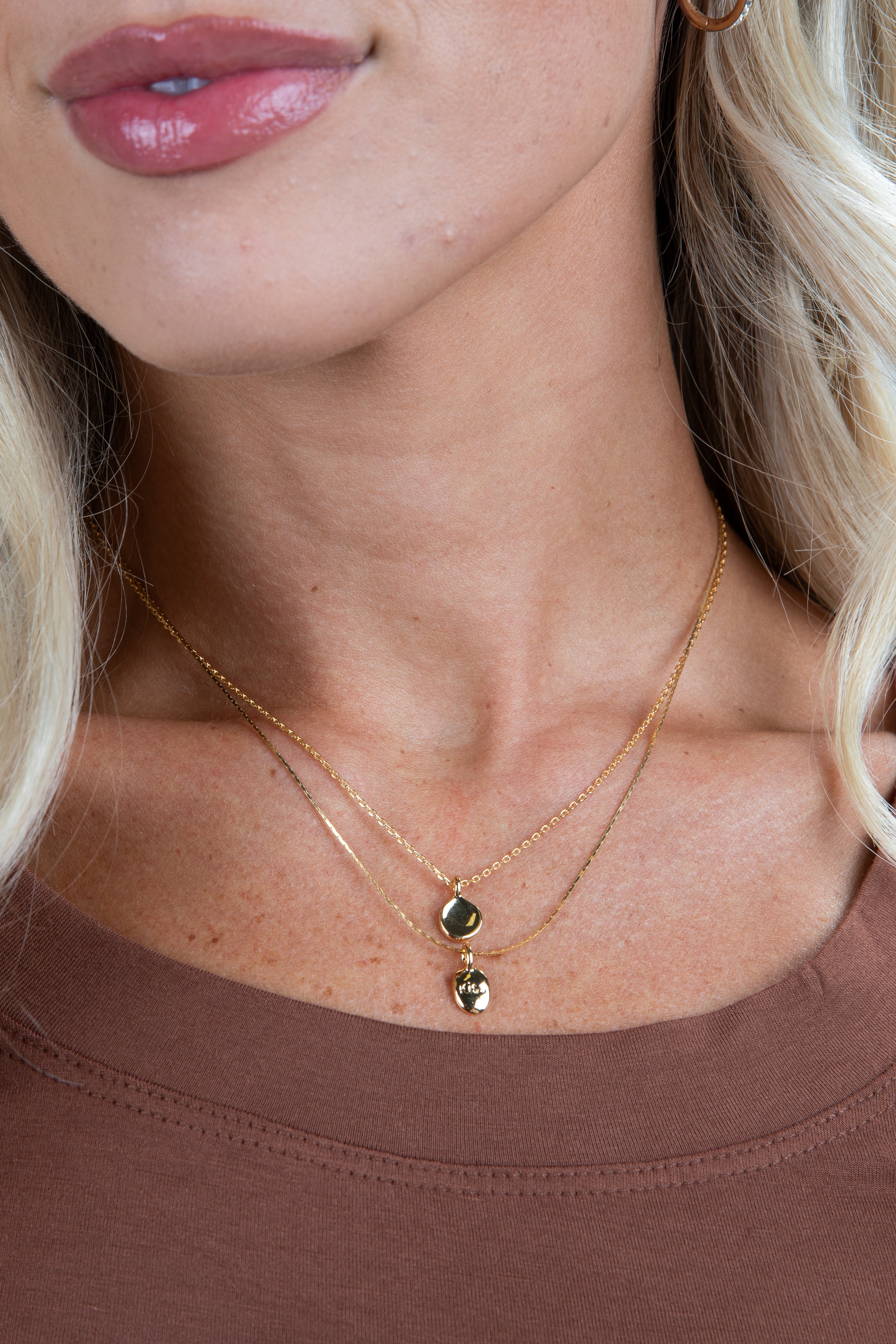 Close-up of a woman wearing a gold necklace with green gemstones.