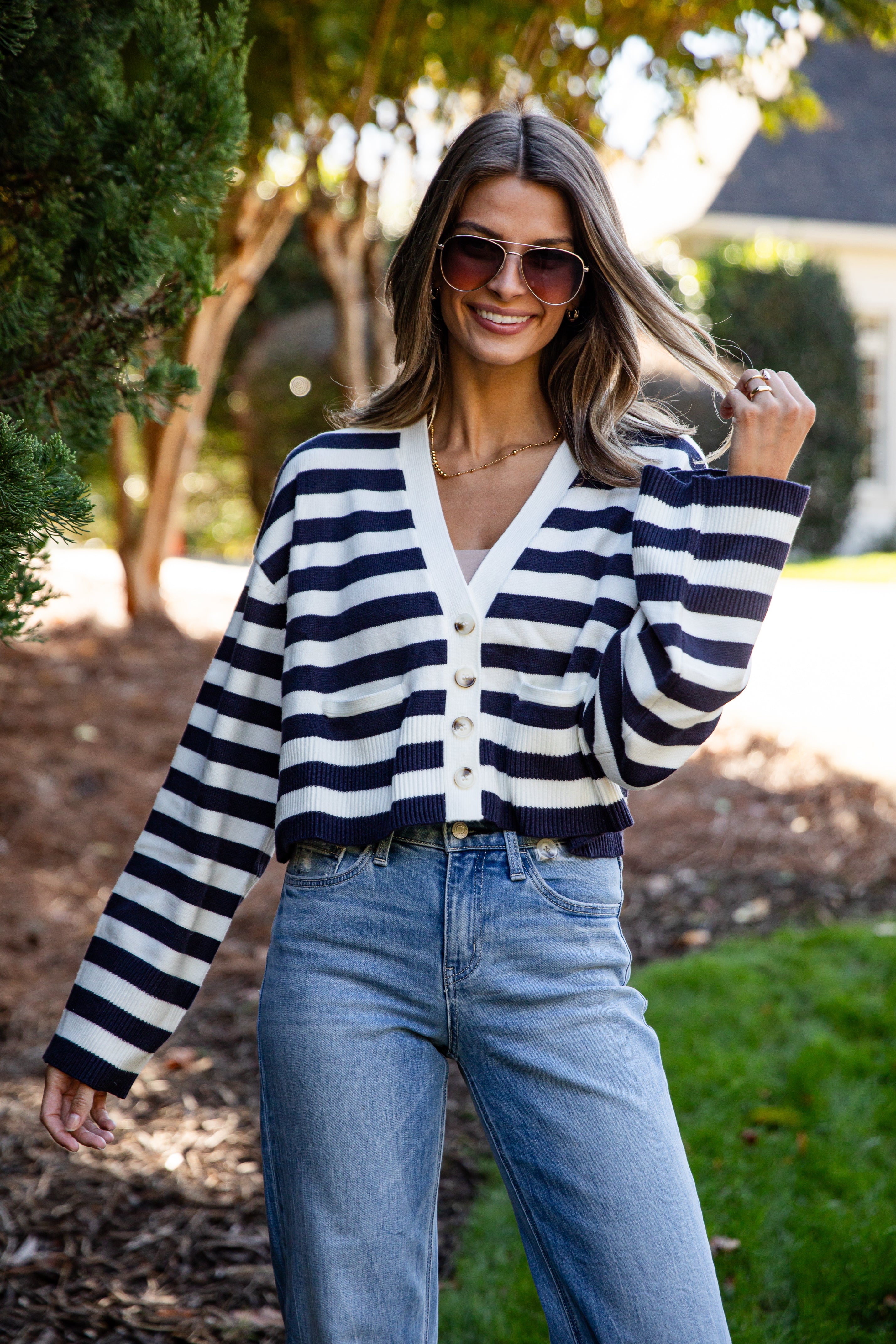 Woman wearing a black and white striped sweater and blue jeans outdoors.