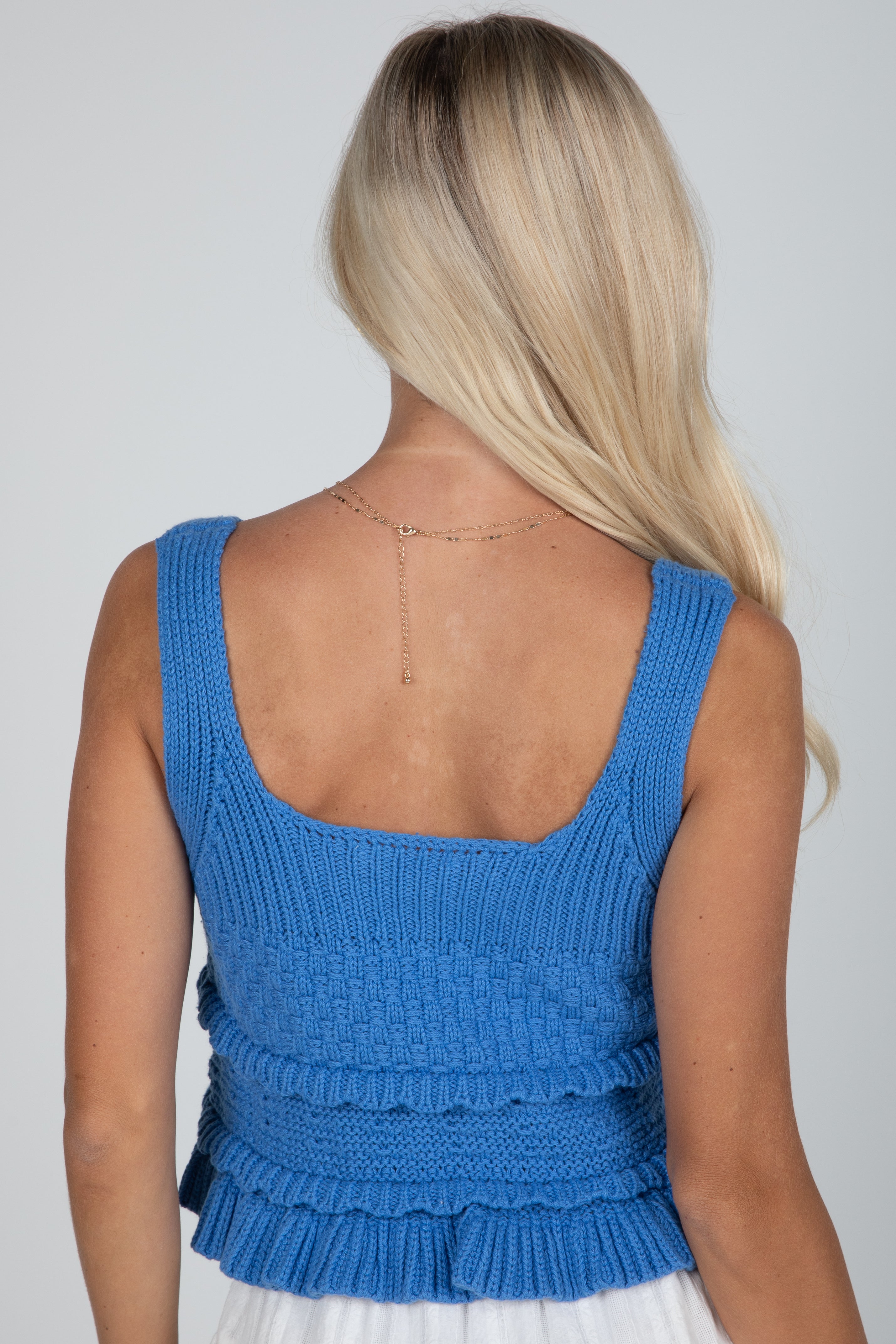 Blue knitted top worn by a person on a plain background