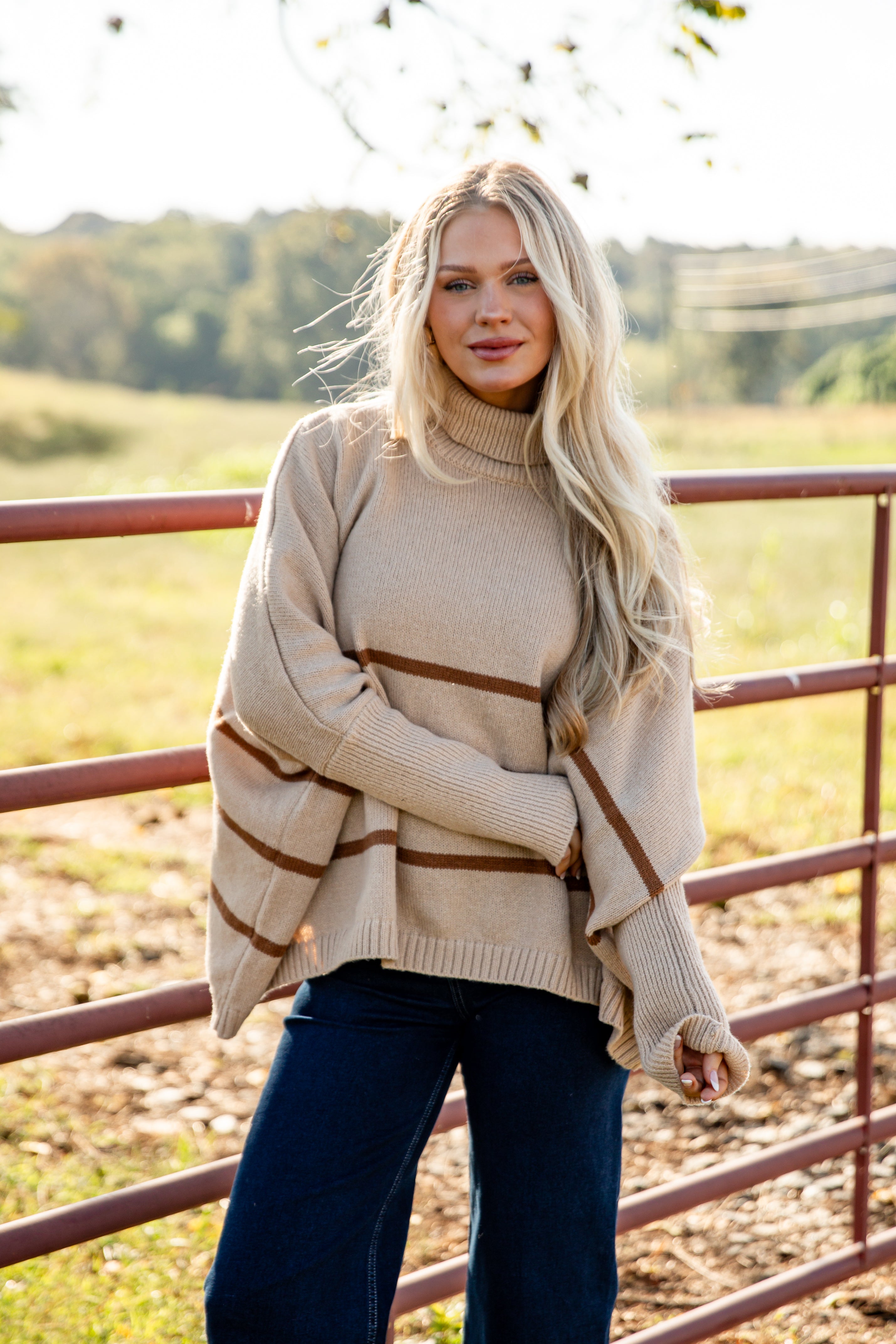 Woman wearing a beige sweater with brown stripes in a field
