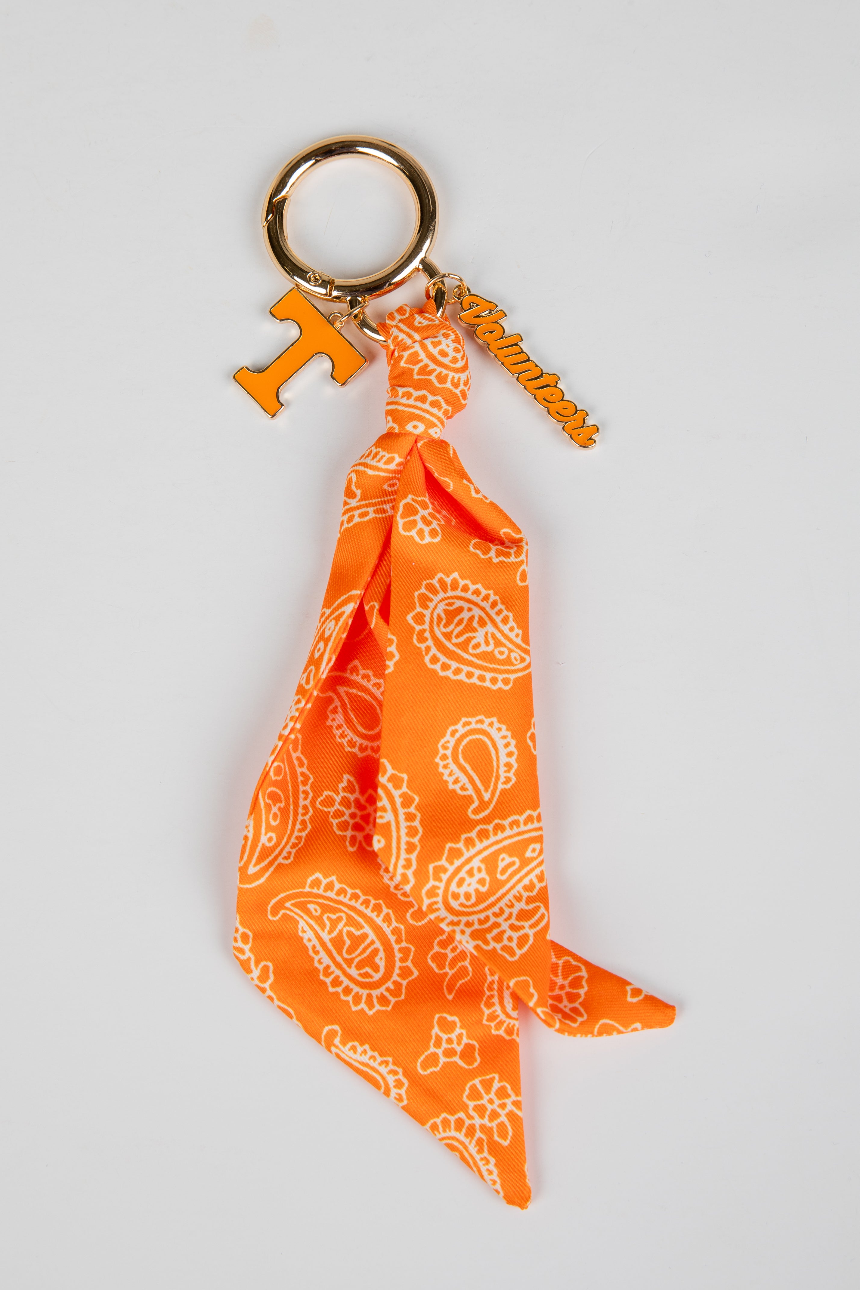 Orange bandana keychain with white patterns on a light gray background