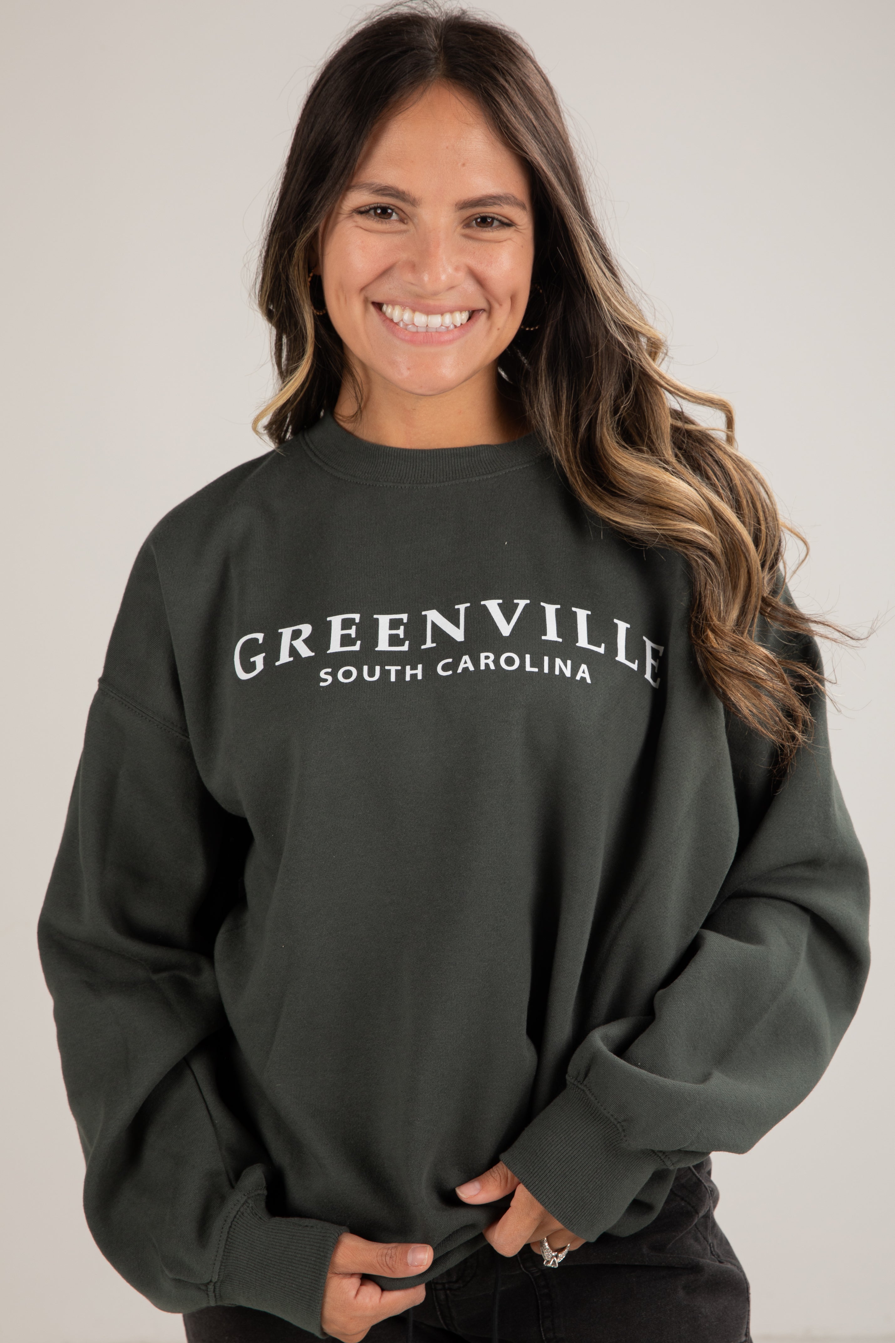 Woman wearing a dark green sweatshirt with &