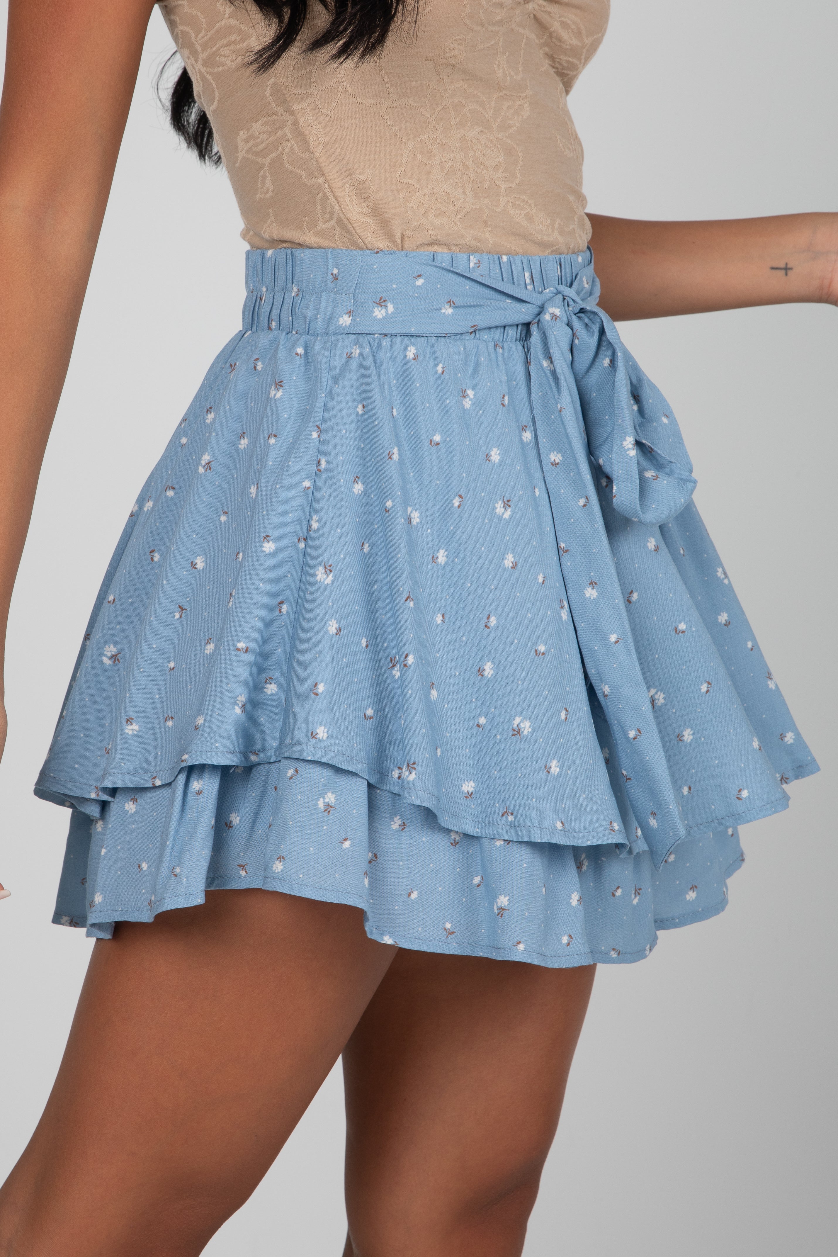 Blue polka dot skirt with a beige top on a plain background